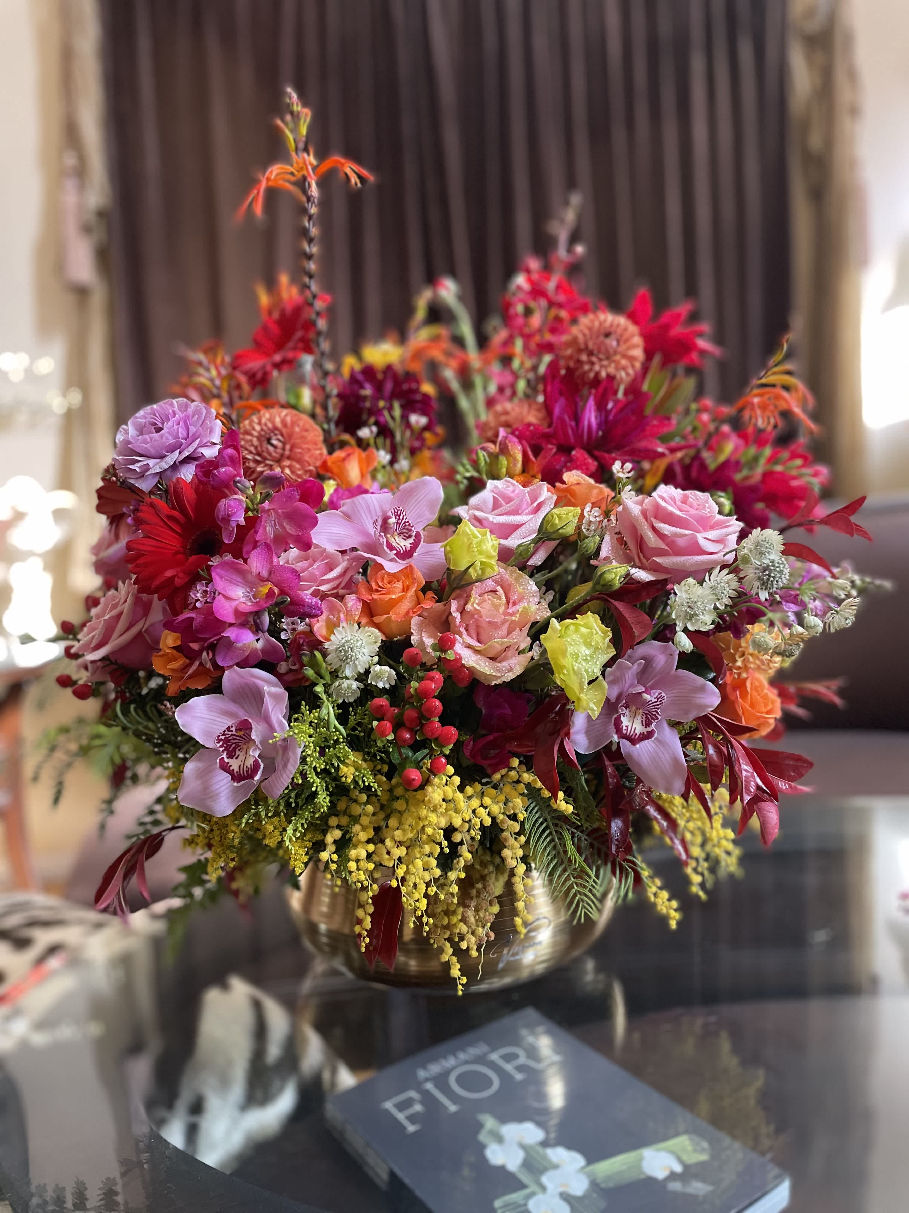 Large mixed bouquet of pink, red, orange, and yellow flowers in a gold vase