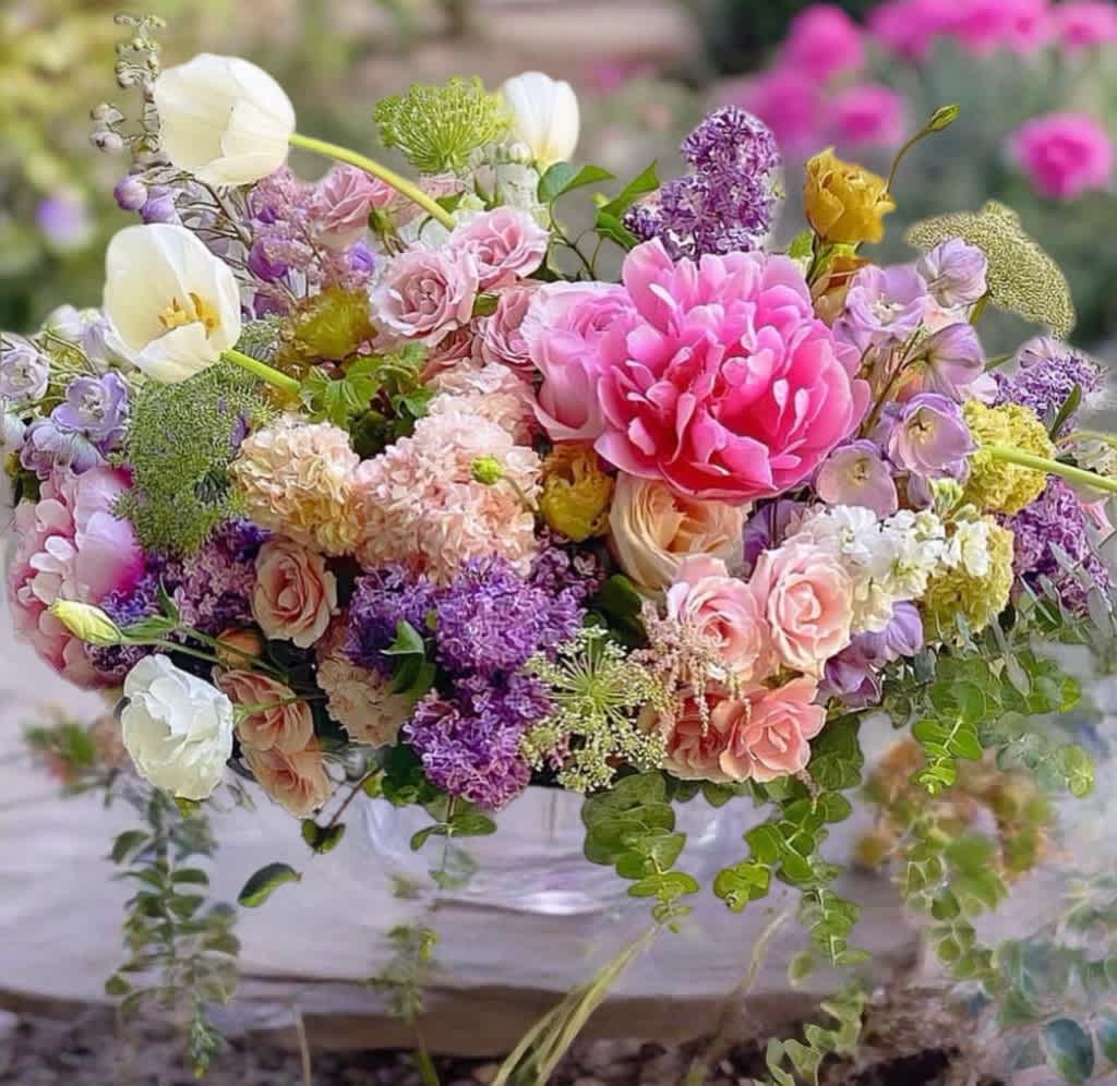 Mixed bouquet of pink, purple, and white flowers in a clear vase