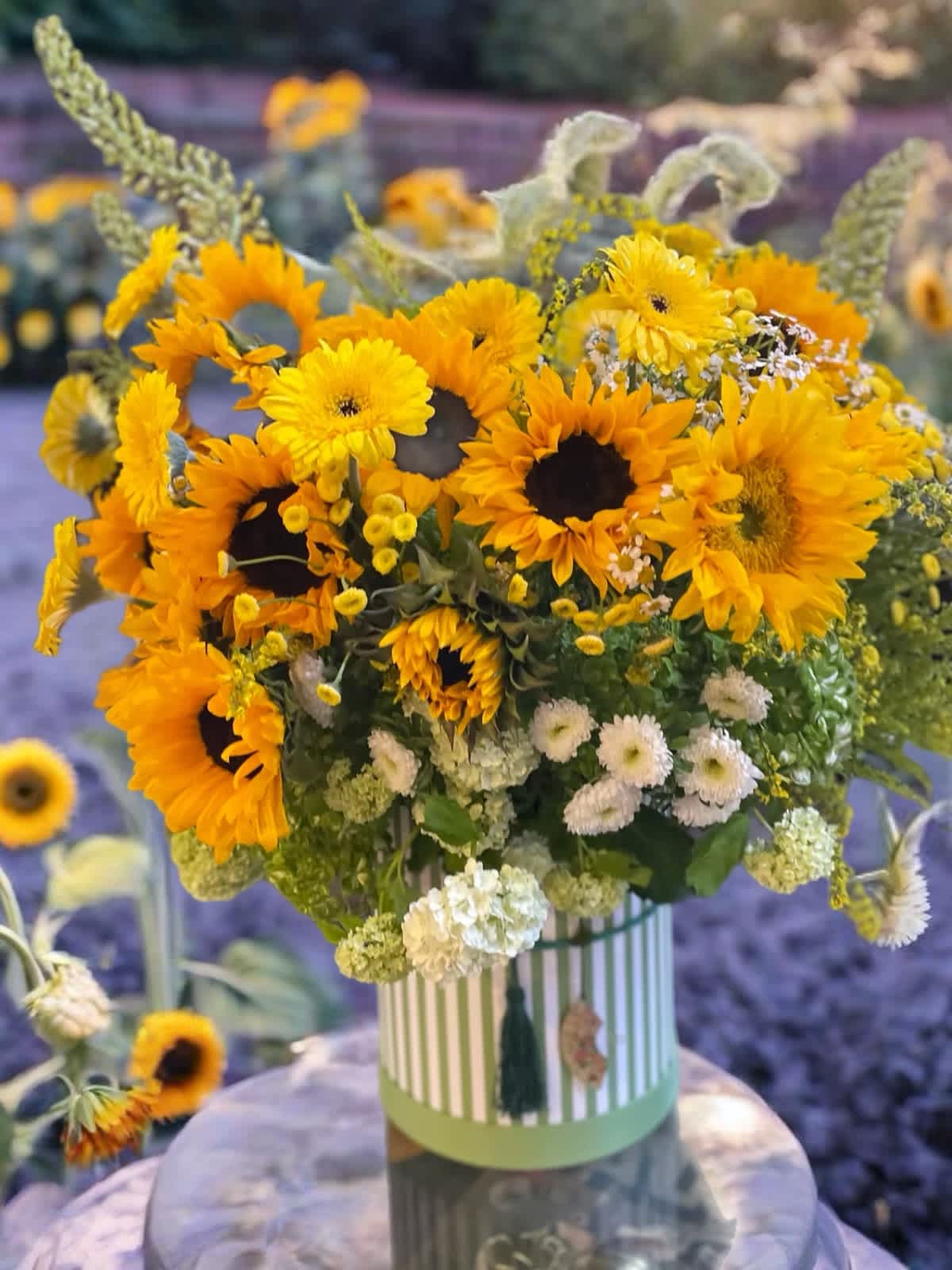 Bouquet of yellow sunflowers and white filler flowers in a striped vase