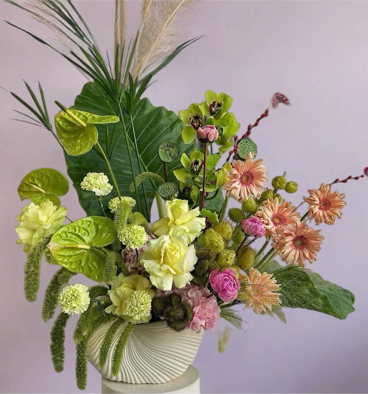 Mixed floral arrangement in a white textured vase with pink and green blooms