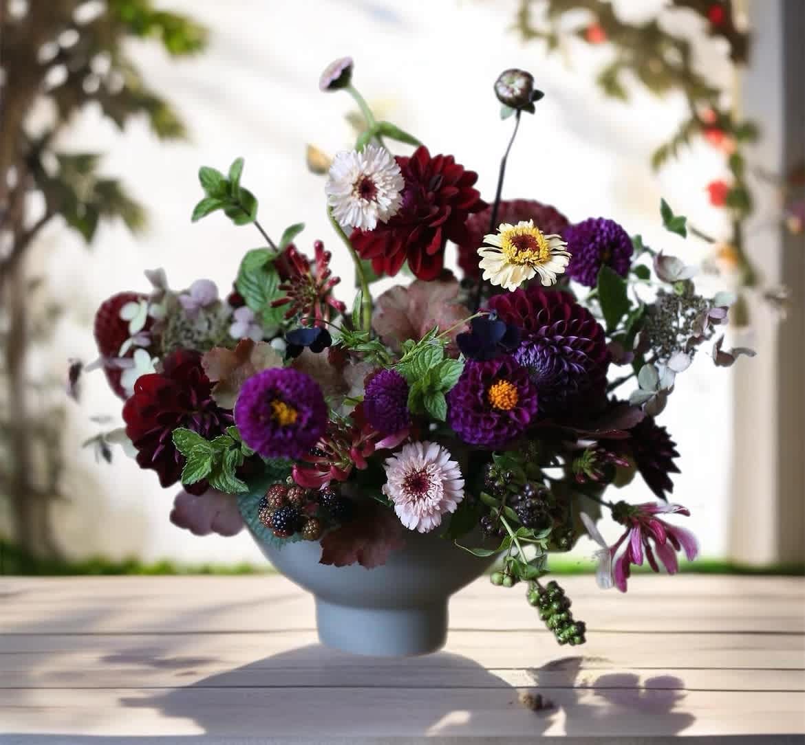 Mixed bouquet of purple, burgundy, and white flowers in a blue vase