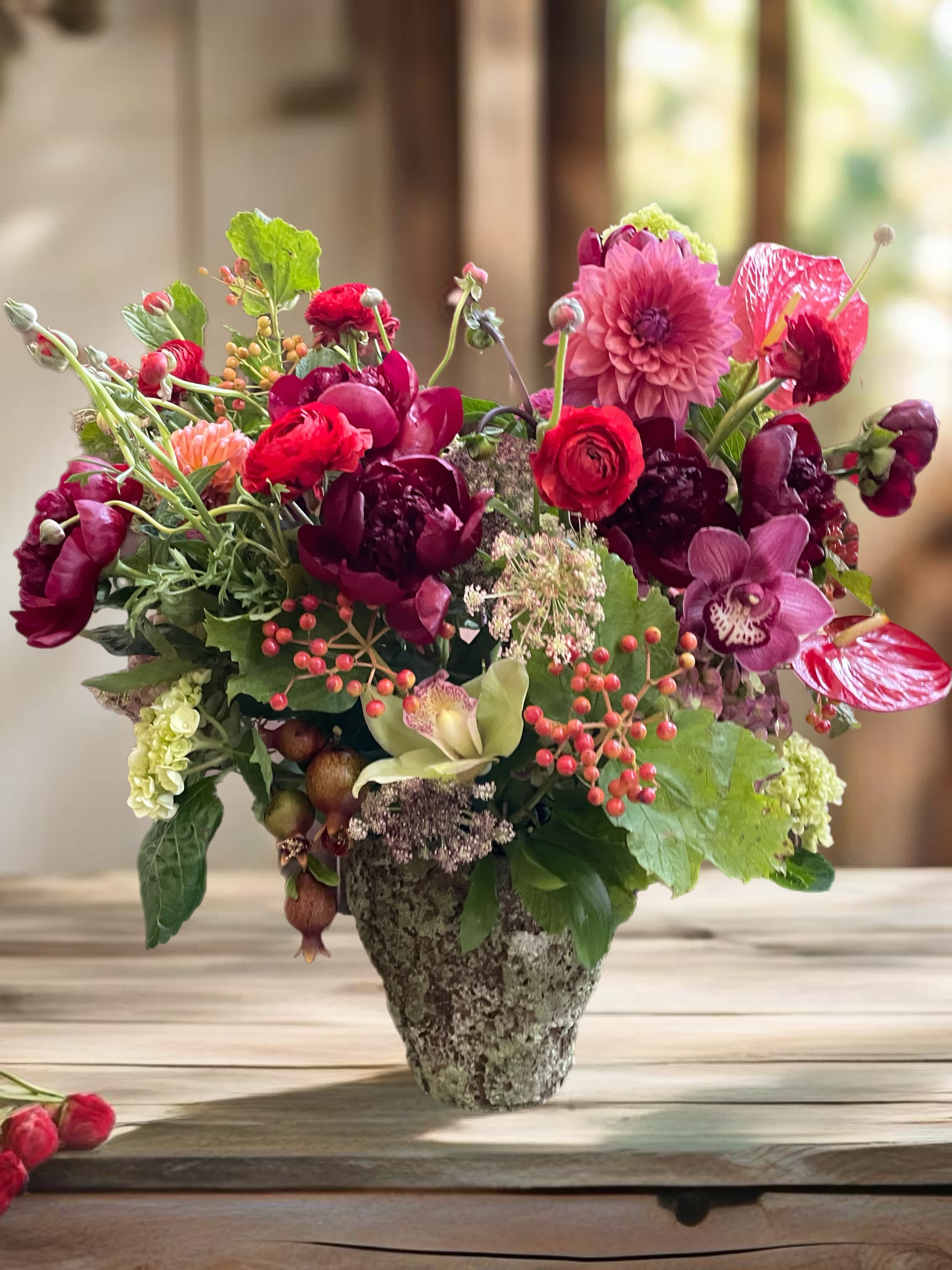 Mixed pink and burgundy flowers arranged in a stone vase