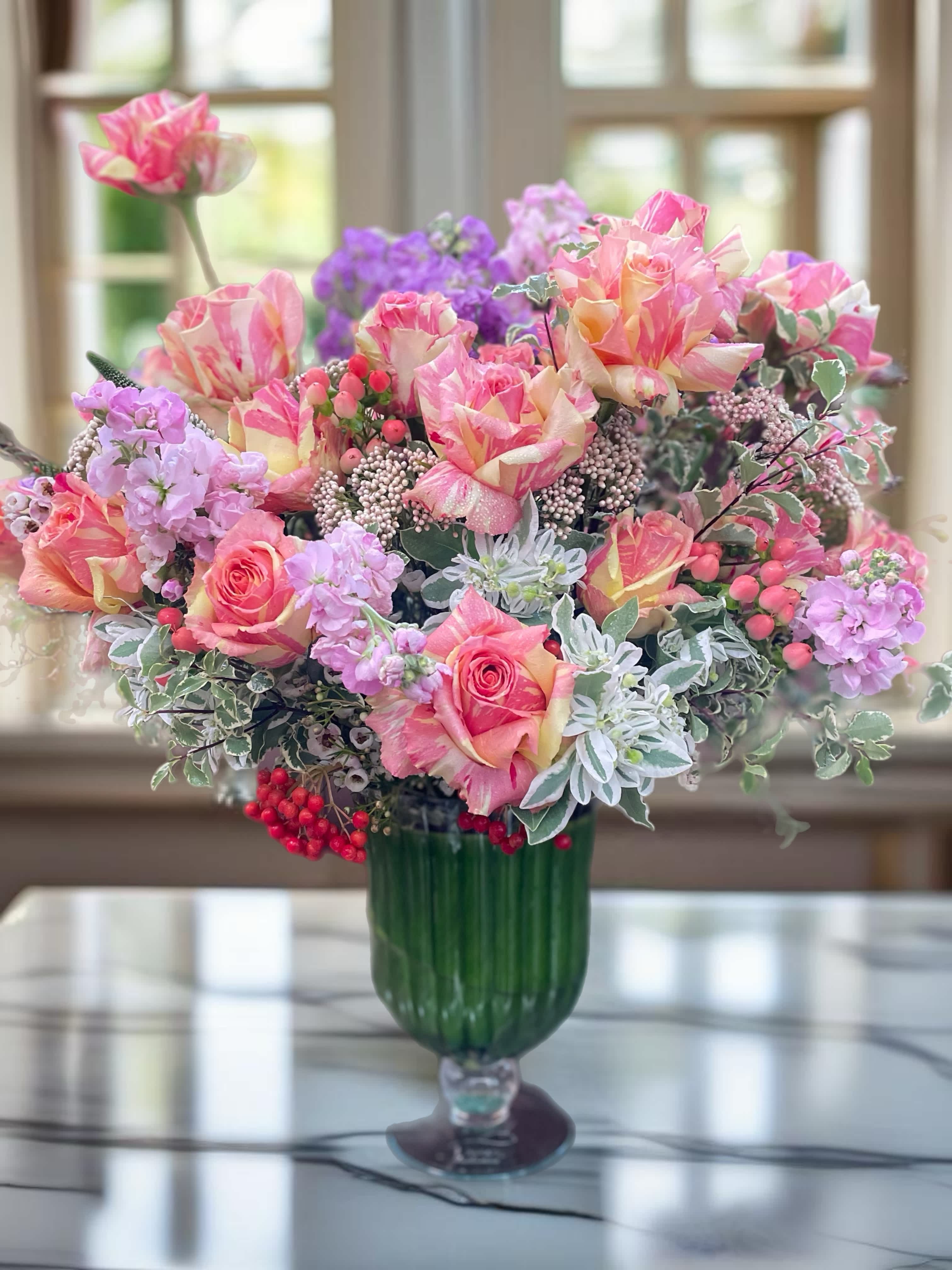 Pink and peach roses arranged in a green glass vase