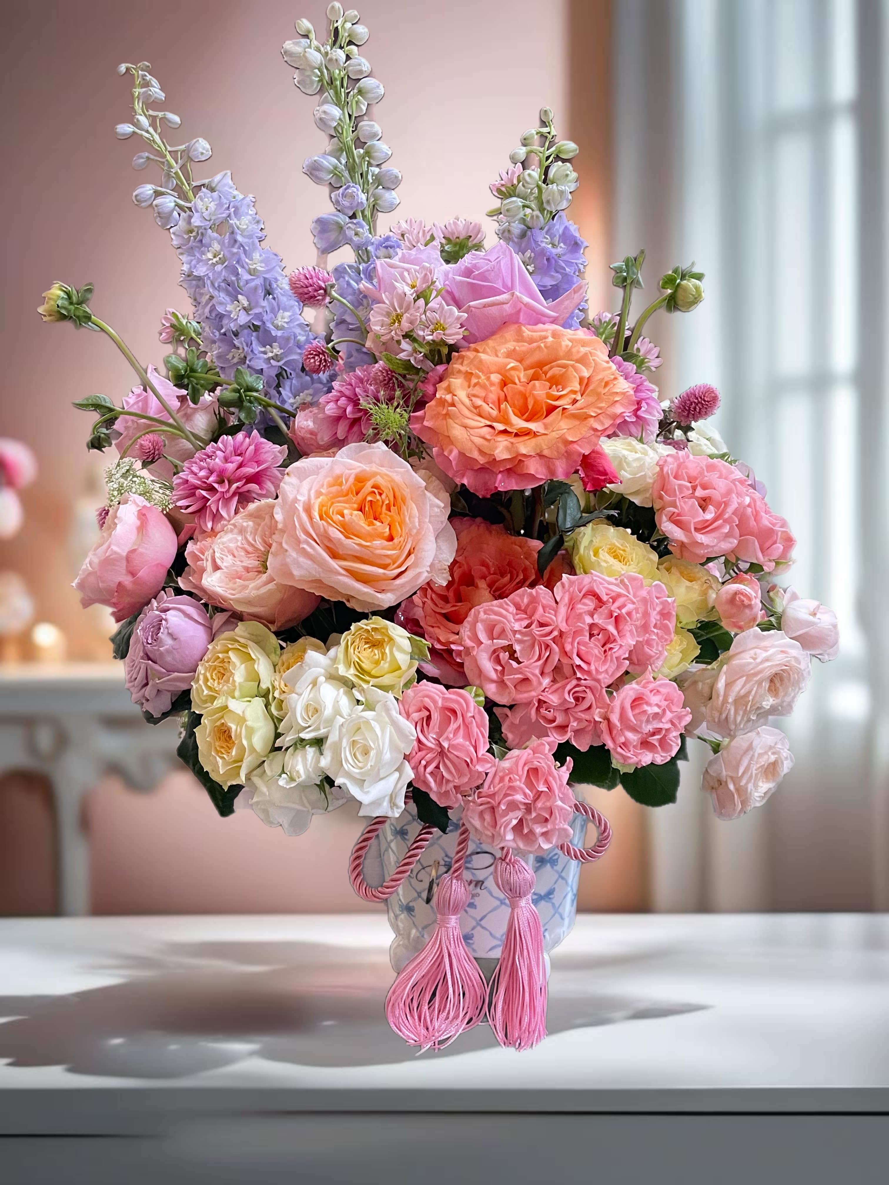 Pastel bouquet of roses, carnations, and delphinium in a decorative vase