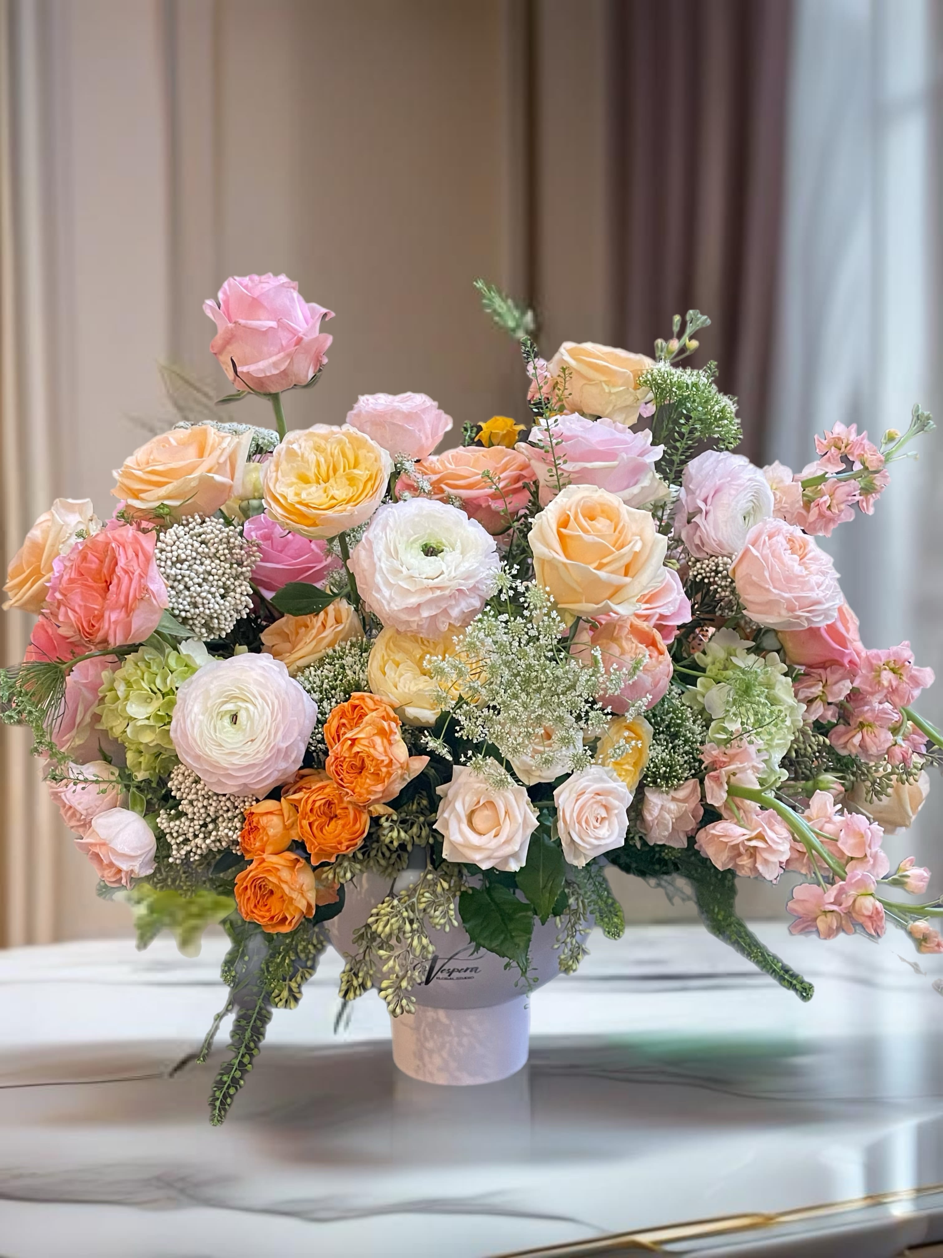 Large pastel rose arrangement in a white vase