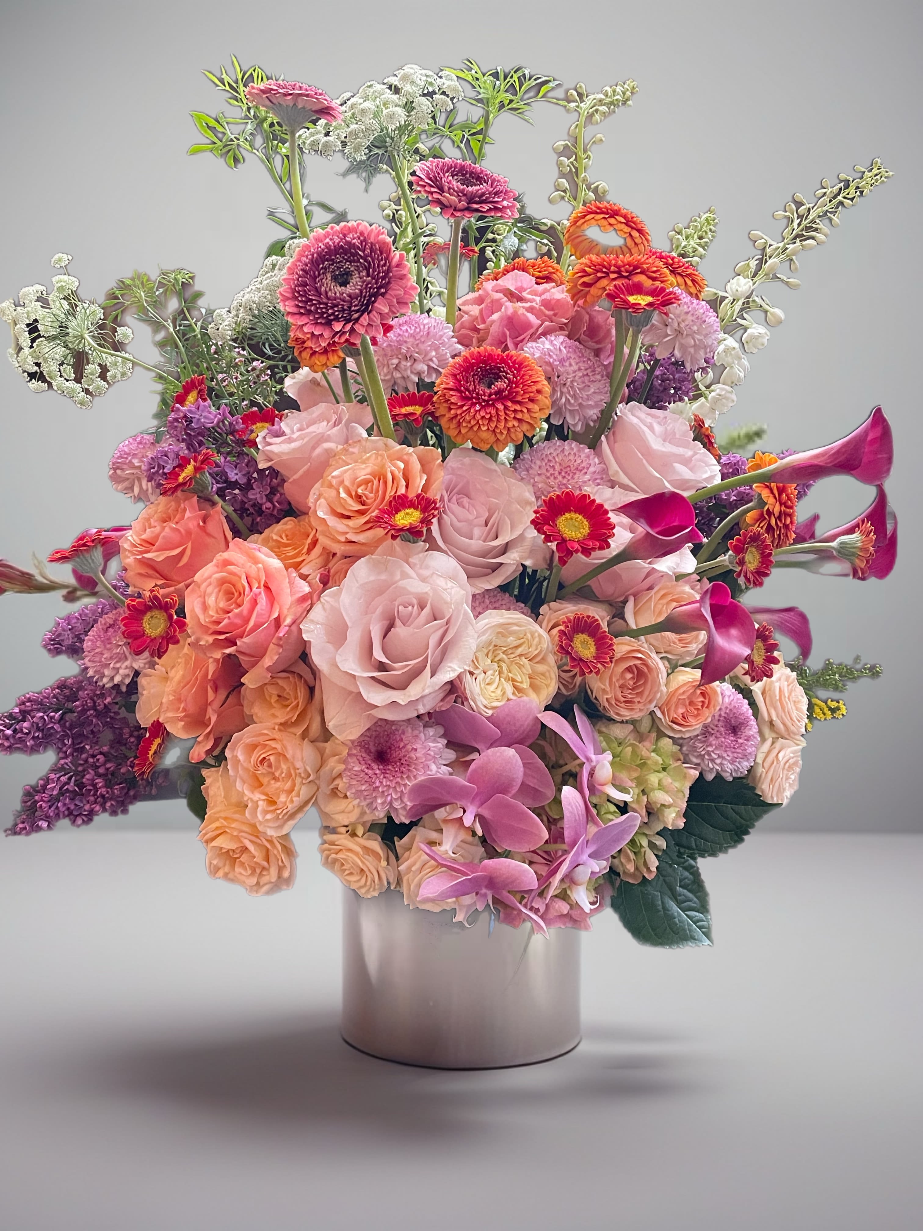 Large mixed bouquet of pink, peach, purple, and white flowers in a vase