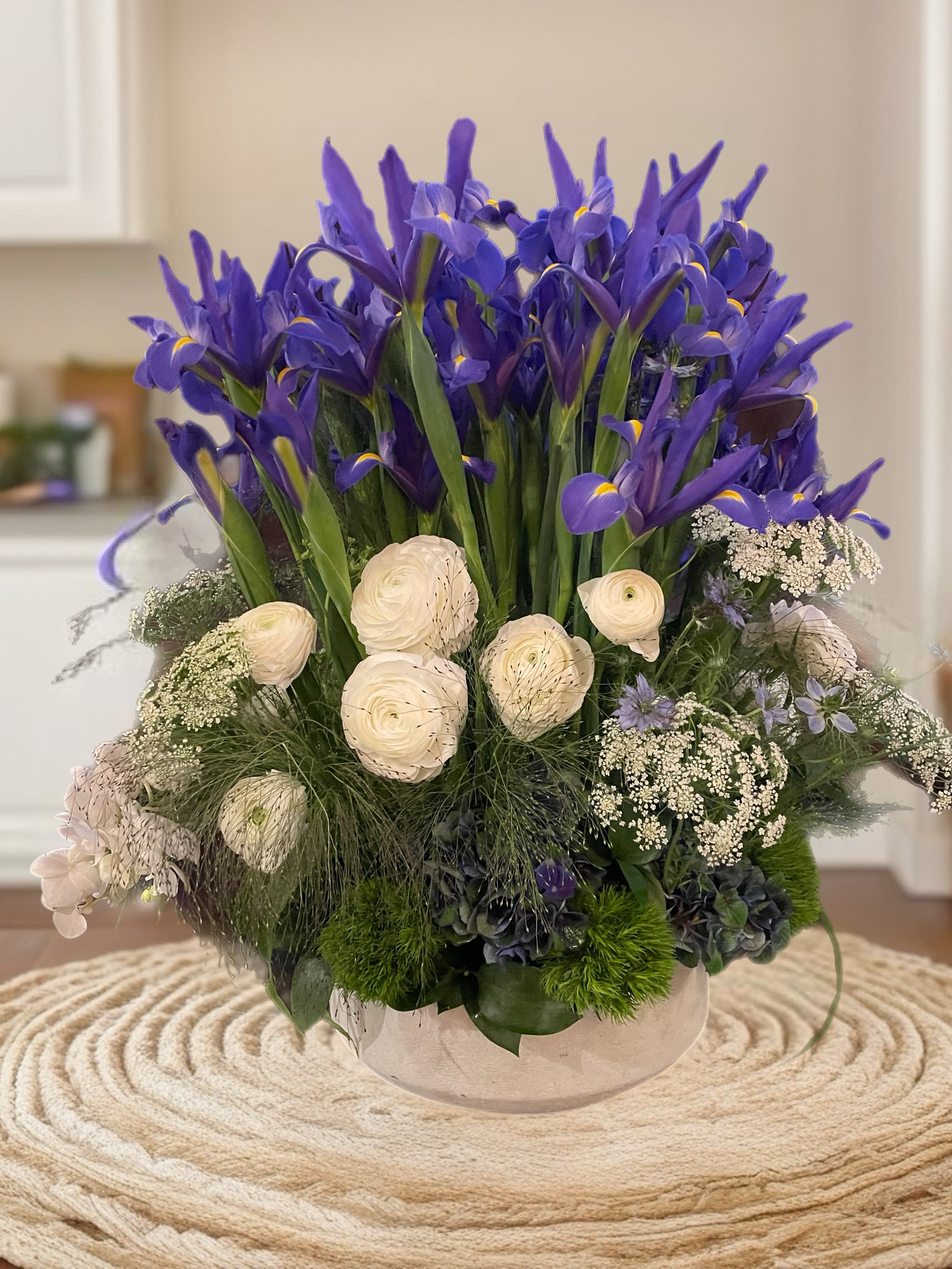 Purple iris arrangement with white blooms in a low glass bowl