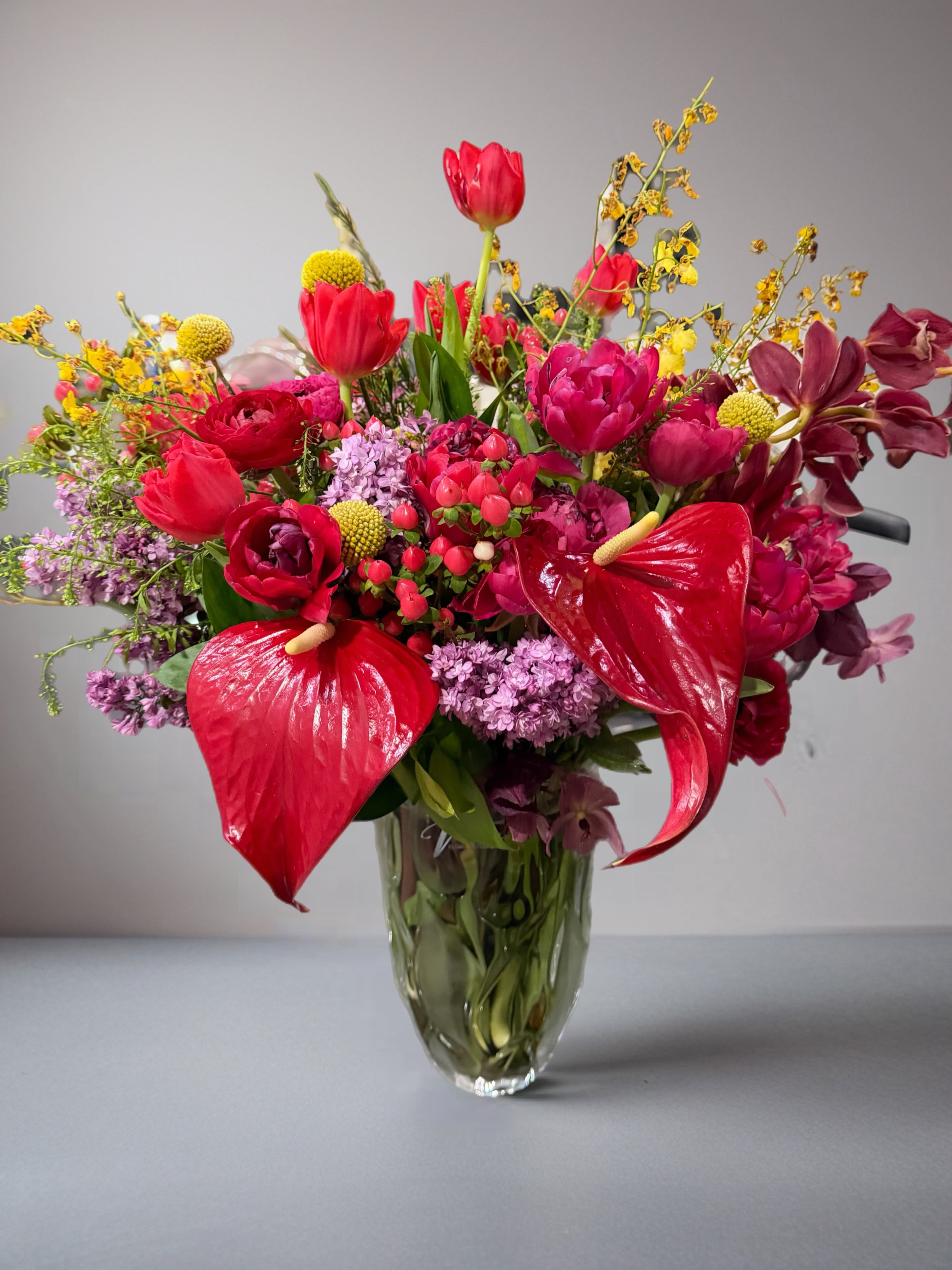 Beautiful spring days  -   Immerse yourself in the essence of spring with a stunning arrangement featuring a harmonious blend of lilacs, tulips, orchids, and anthurium hearts. Each bloom dances together in a symphony of colors, celebrating love and new beginnings. This captivating display embodies the spirit of spring, radiating joy and freshness through its bright, vivid hues.  