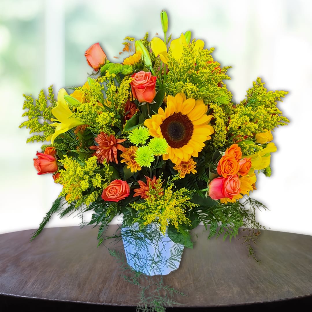 Bright mixed bouquet with sunflowers, roses, and lilies in a white vase