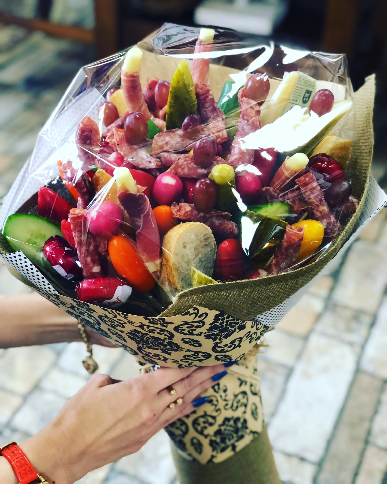 Bouquet of assorted salami, cheese, and grapes wrapped in decorative paper