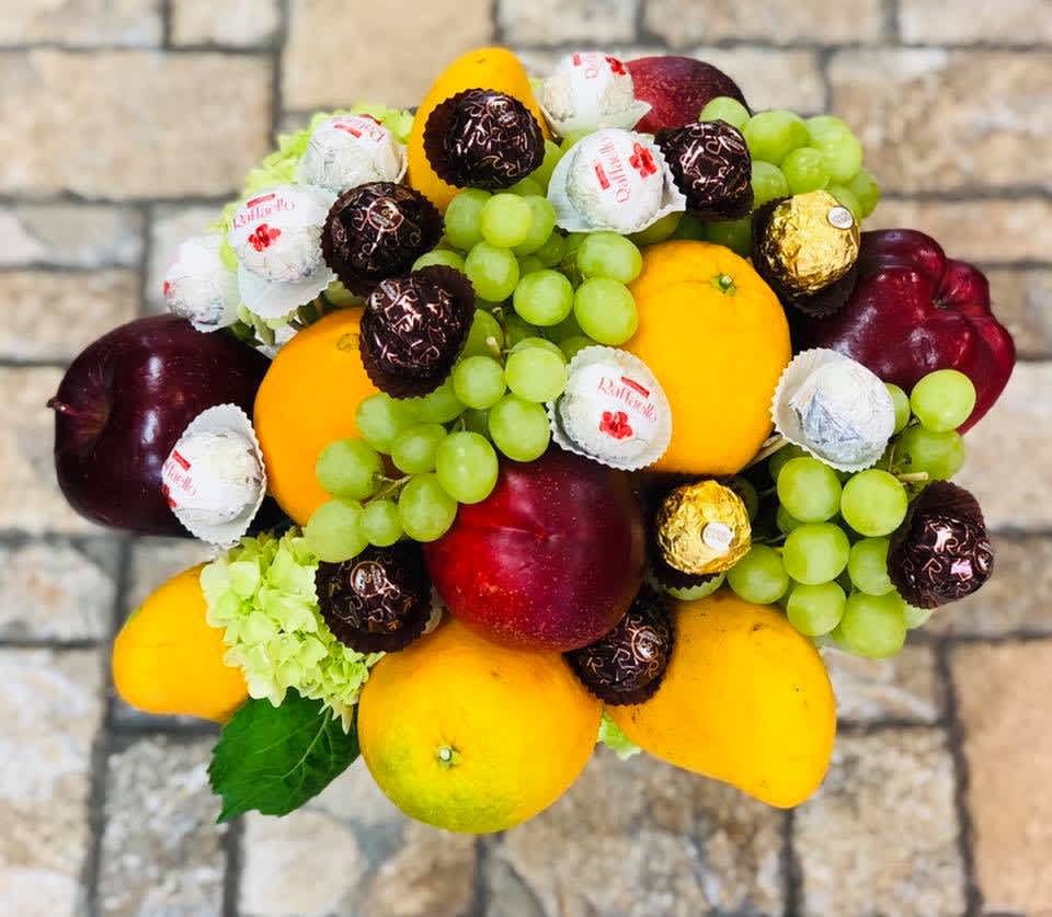 Fruit arrangement with grapes, mangoes, apples, and wrapped chocolates