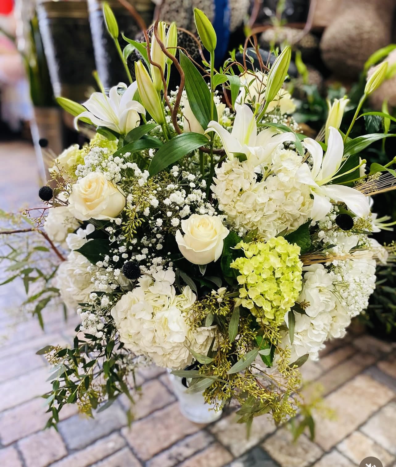 White lilies and roses arranged with hydrangeas in a vase