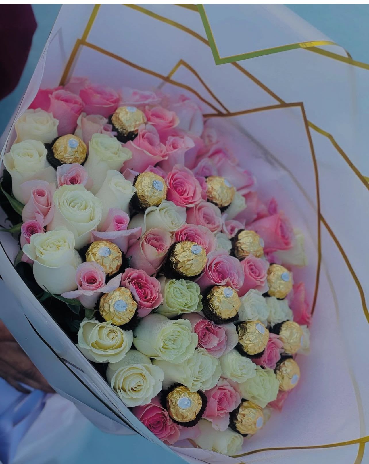 Bouquet of pink and white roses with gold-wrapped chocolates