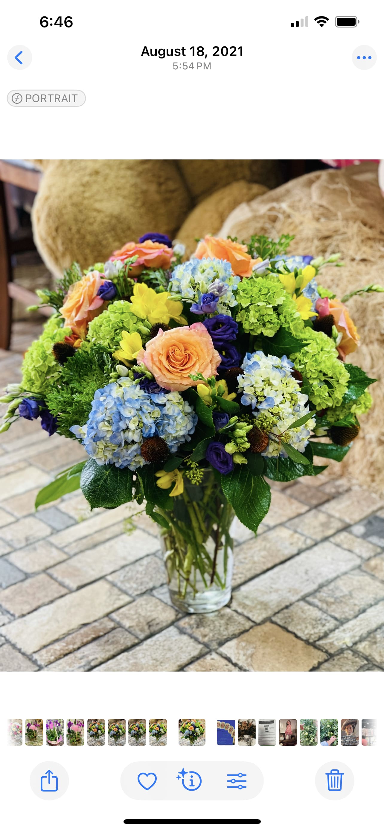 Mixed bouquet in a clear glass vase with peach roses and blue hydrangeas