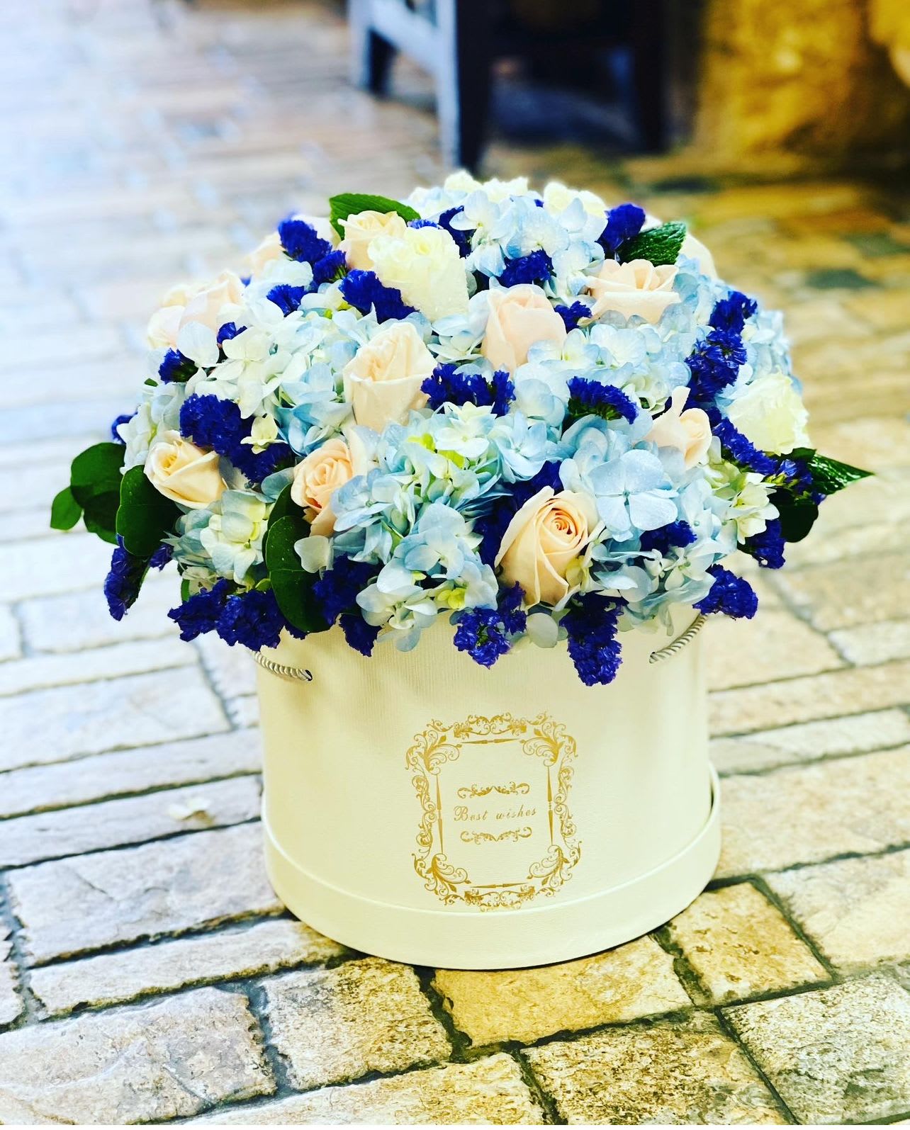 Blue and cream flower arrangement in a round white box