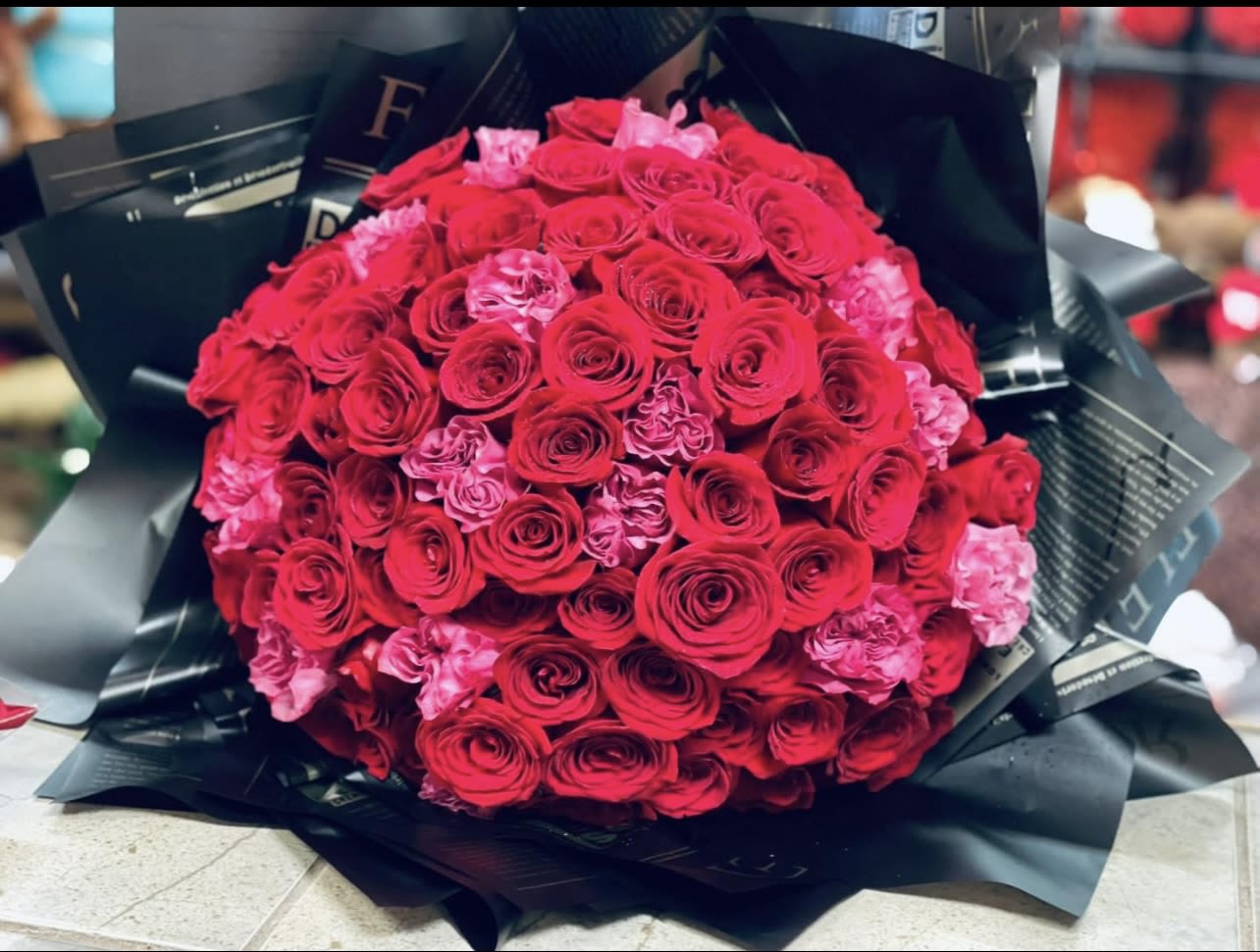 Large bouquet of red and pink roses wrapped in black paper