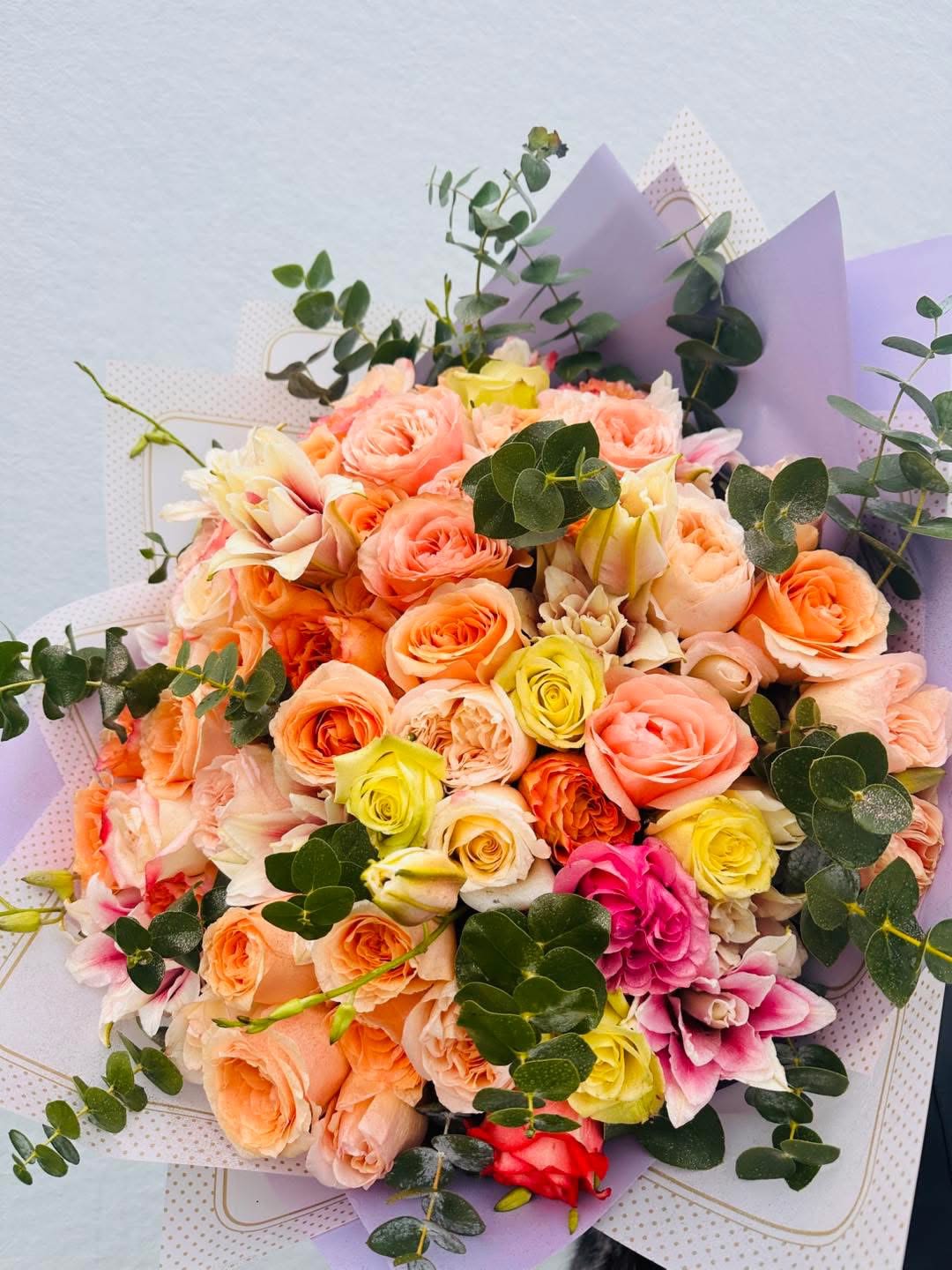 Bouquet of peach, pink, and yellow roses with eucalyptus
