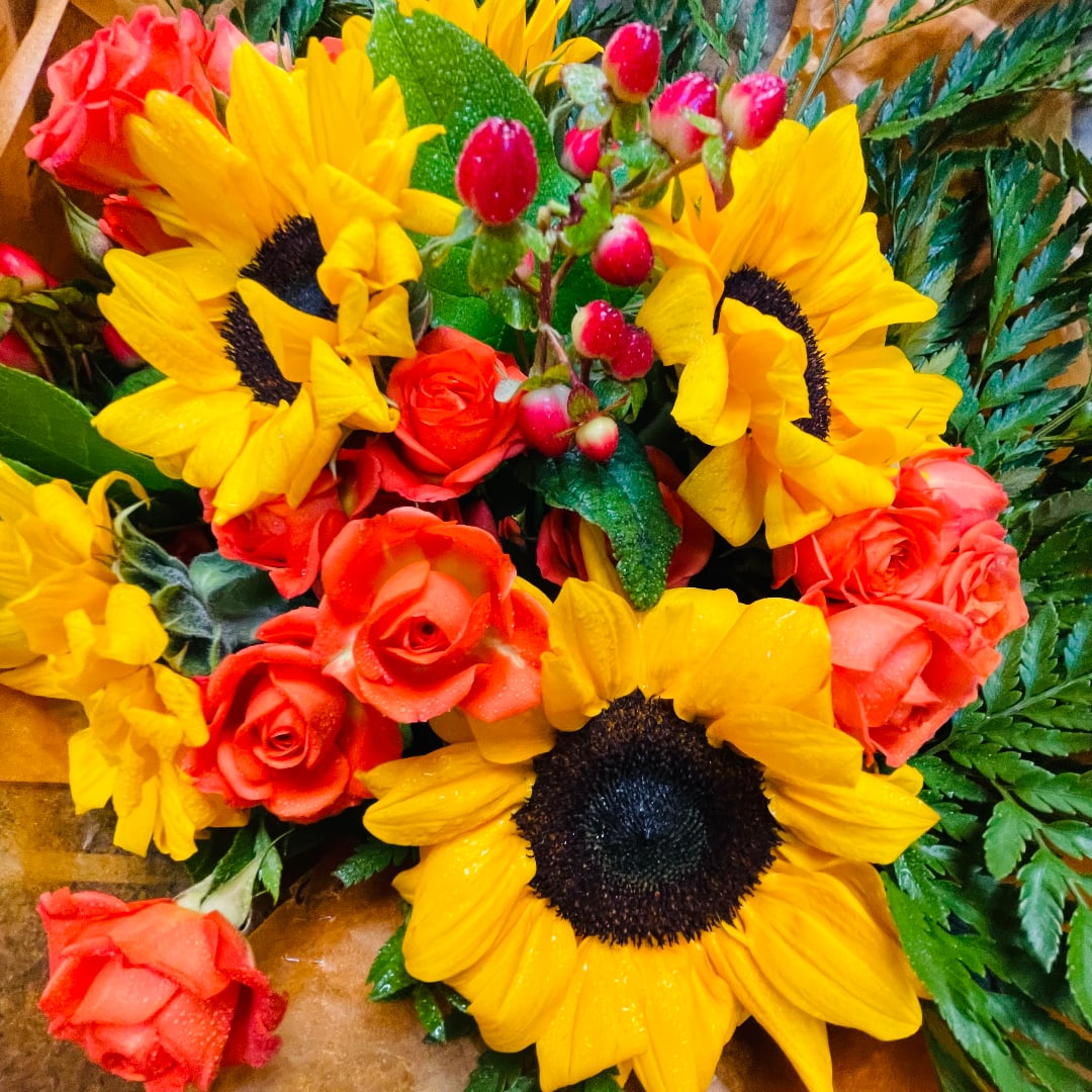 Bouquet of yellow sunflowers and orange roses with red berry accents
