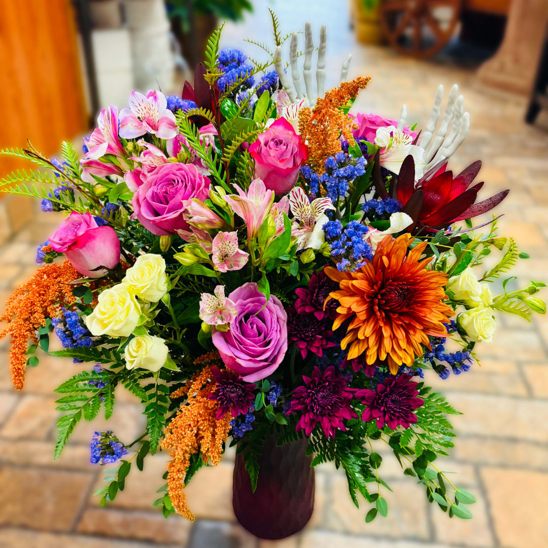Colorful mixed bouquet in a dark vase with roses and daisies