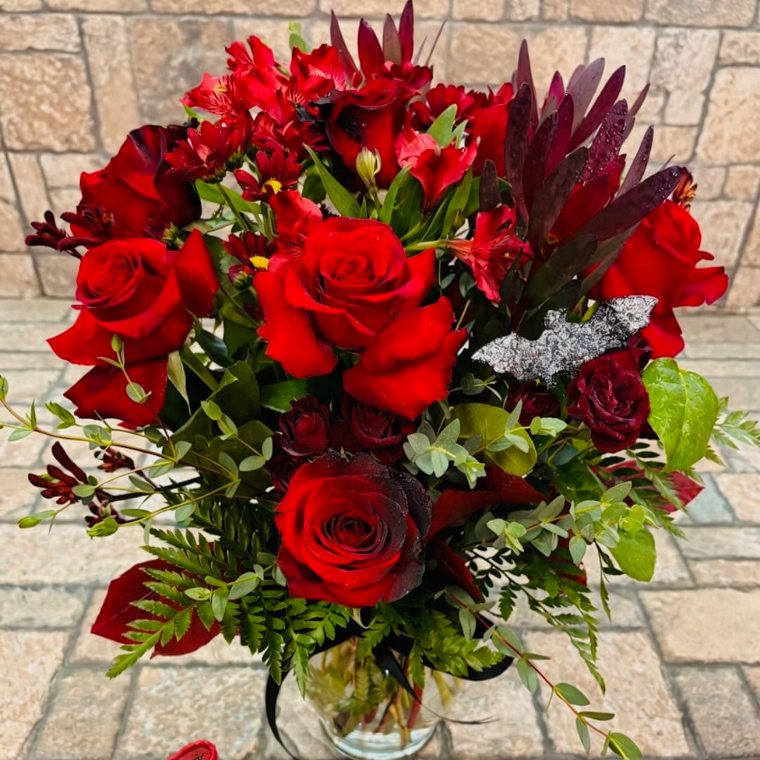 Red rose bouquet in a clear glass vase with mixed greenery