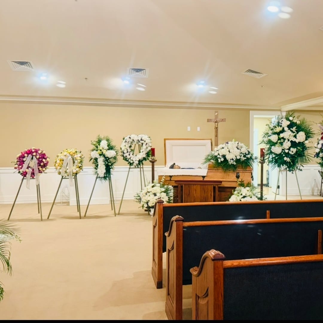 Funeral chapel with white floral wreaths and sprays around a casket