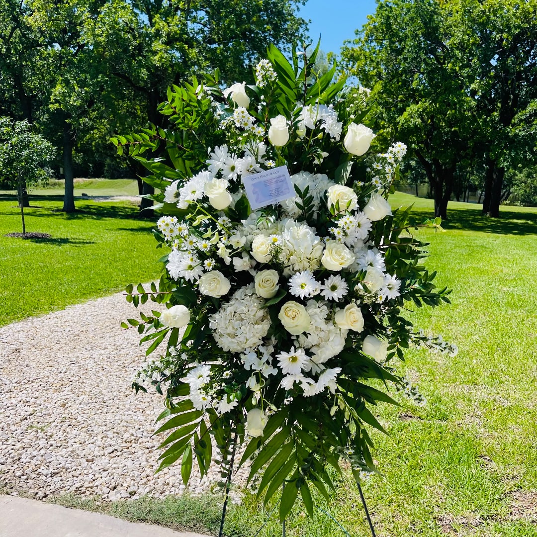 Large white floral standing spray on an easel outdoors