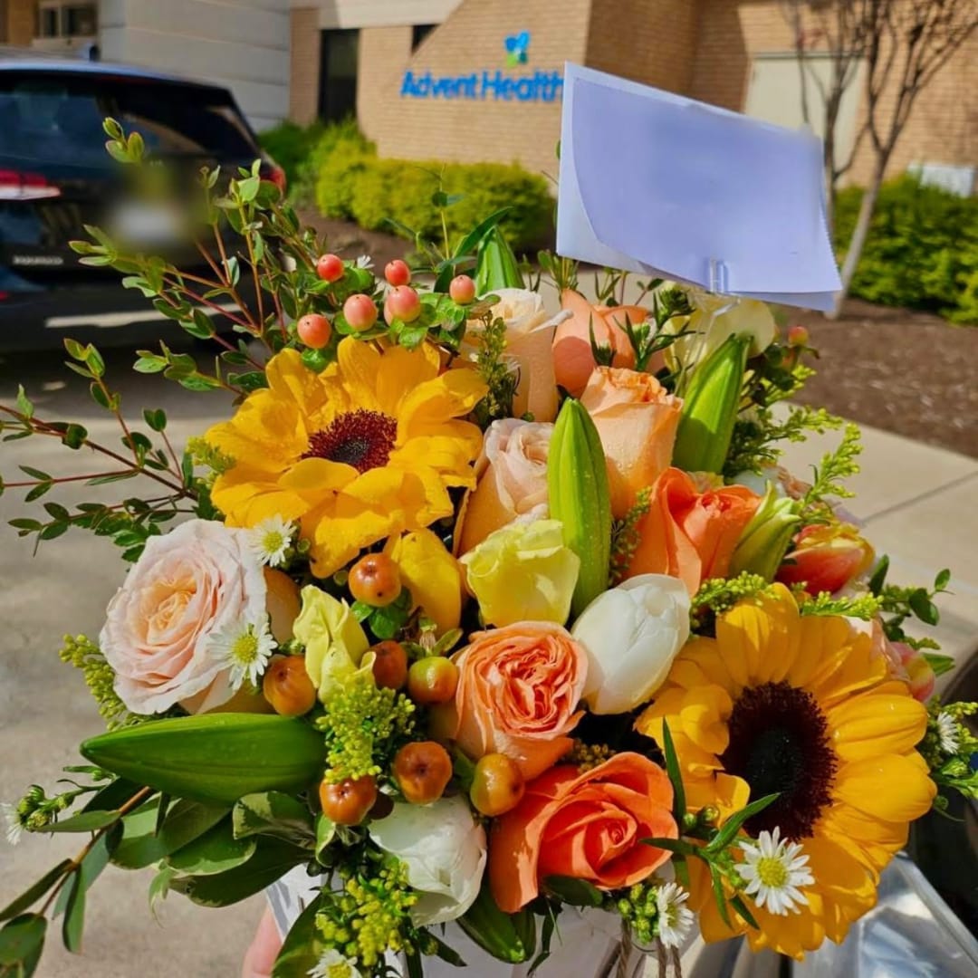 Bouquet of yellow sunflowers, peach roses, and white lilies with a blank card