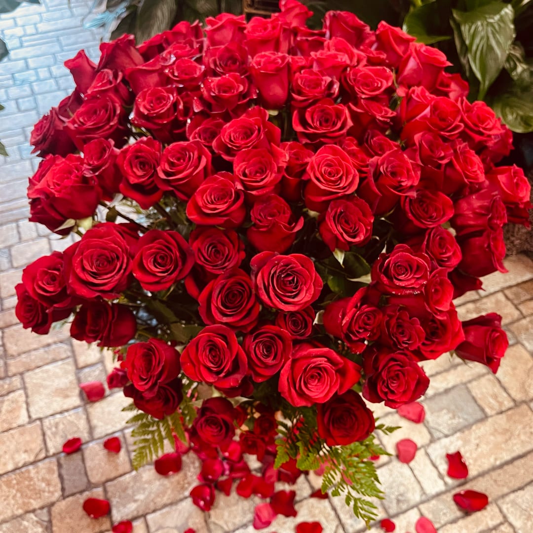 Large bouquet of red roses with scattered petals on the ground