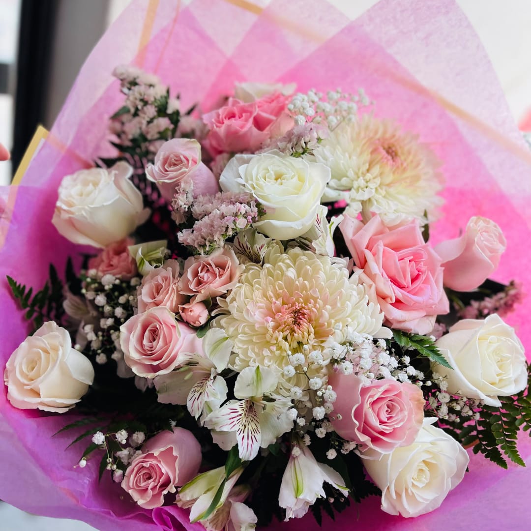 Bouquet of pink and white roses with pale chrysanthemums wrapped in pink paper