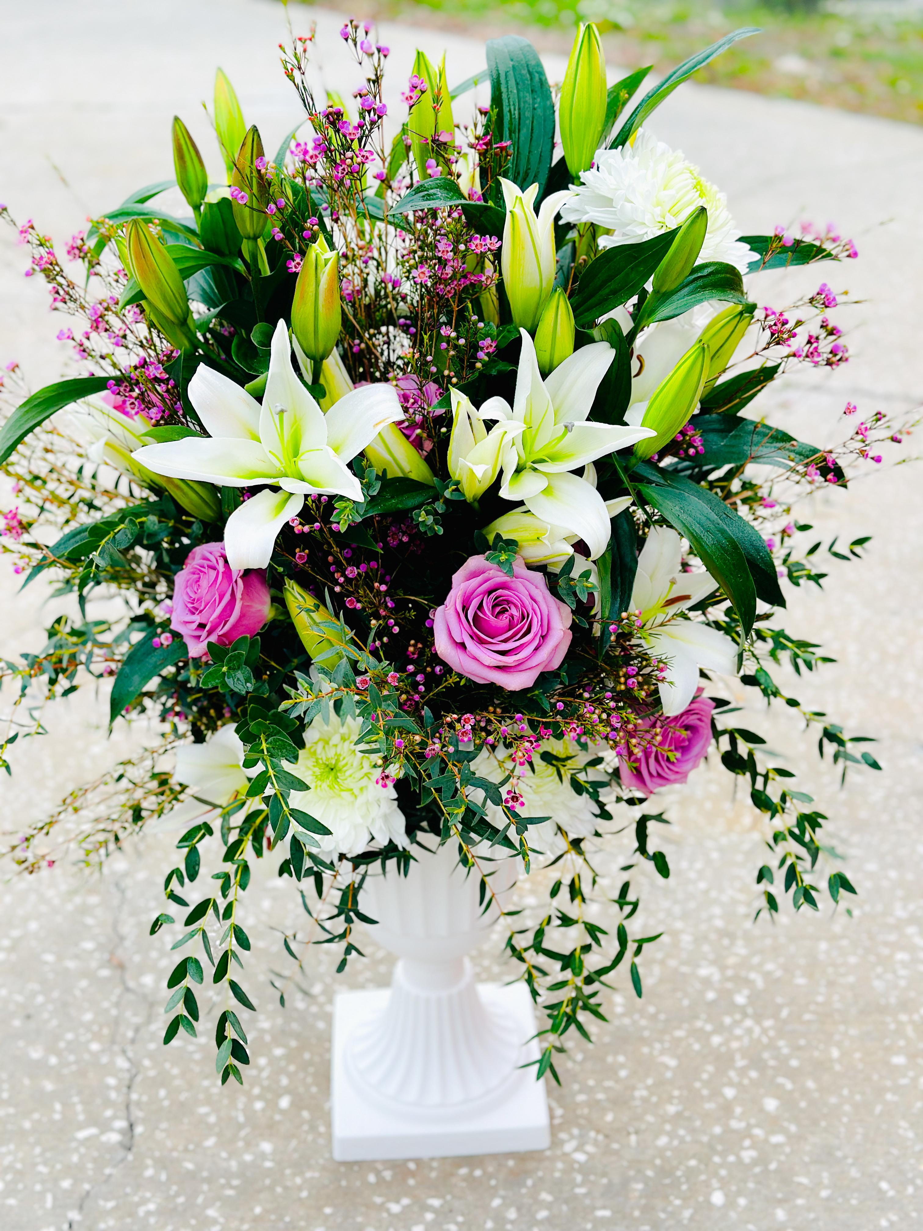 White lilies and pink roses arranged in a white pedestal vase