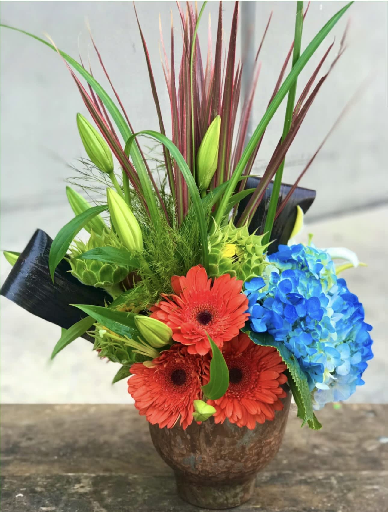 Bright mixed bouquet with red gerberas and blue hydrangea in a brown vase