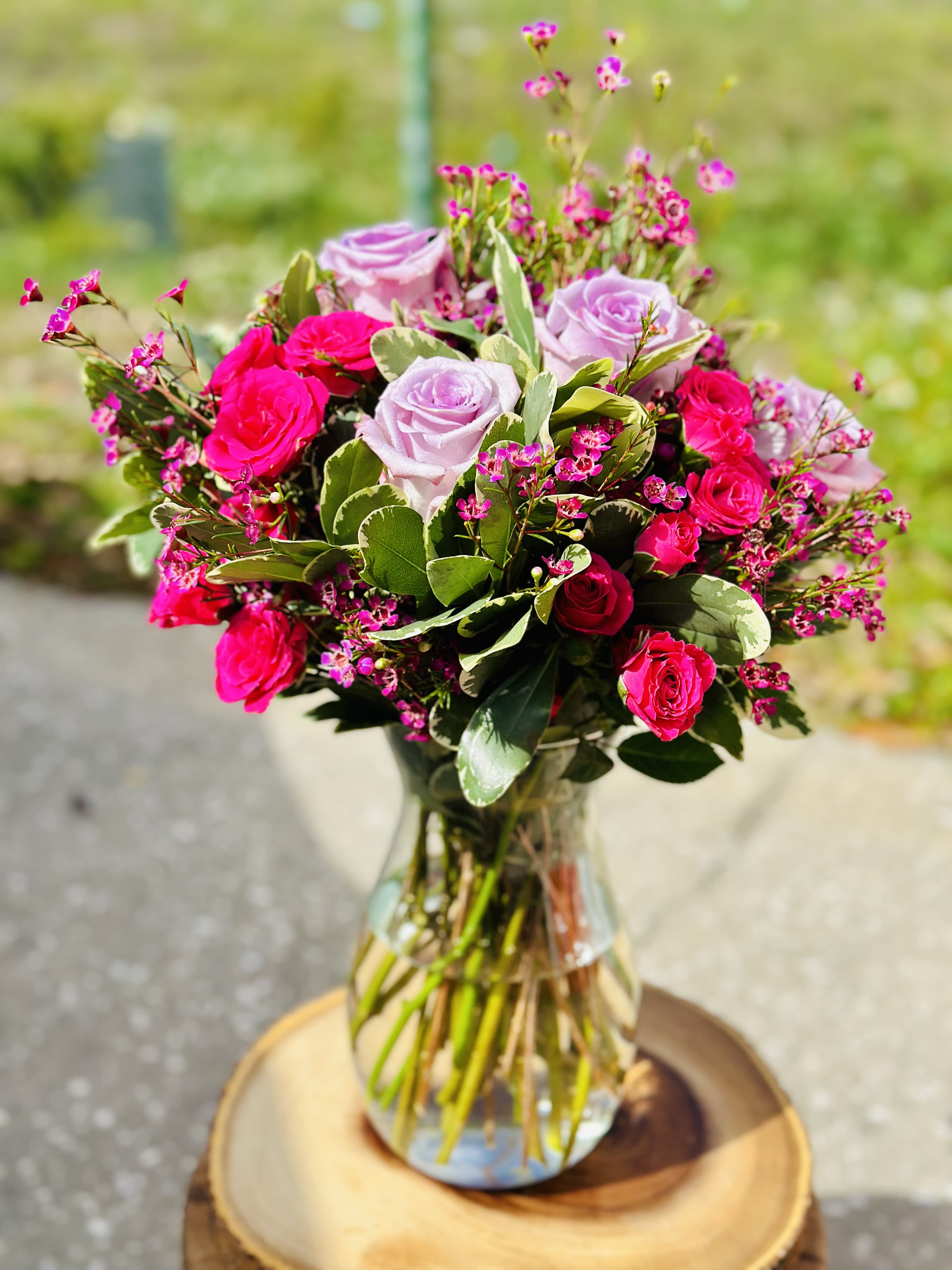Pink and lavender roses arranged in a clear glass vase