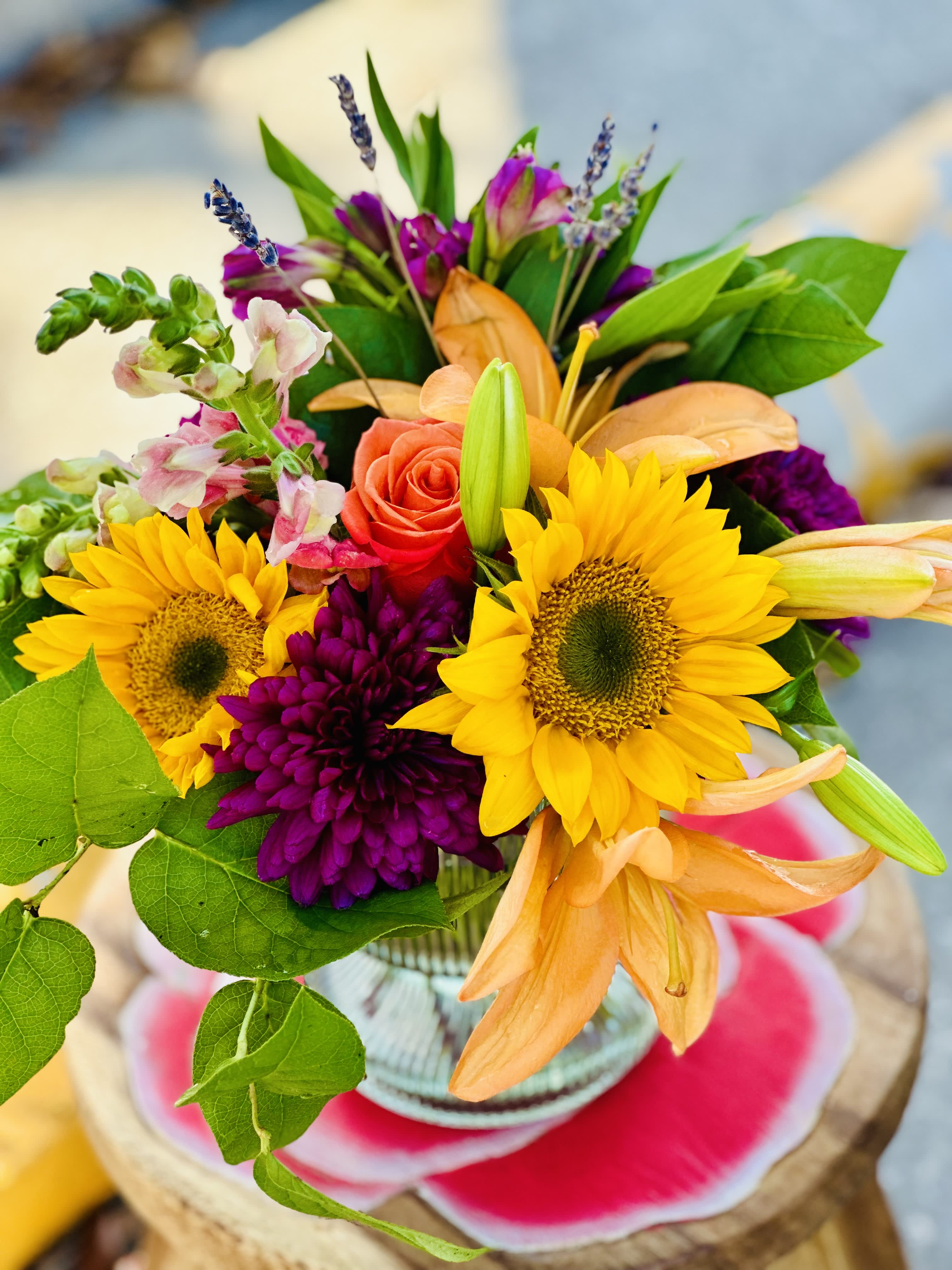Bouquet with sunflowers, roses, and orange lilies in a glass vase