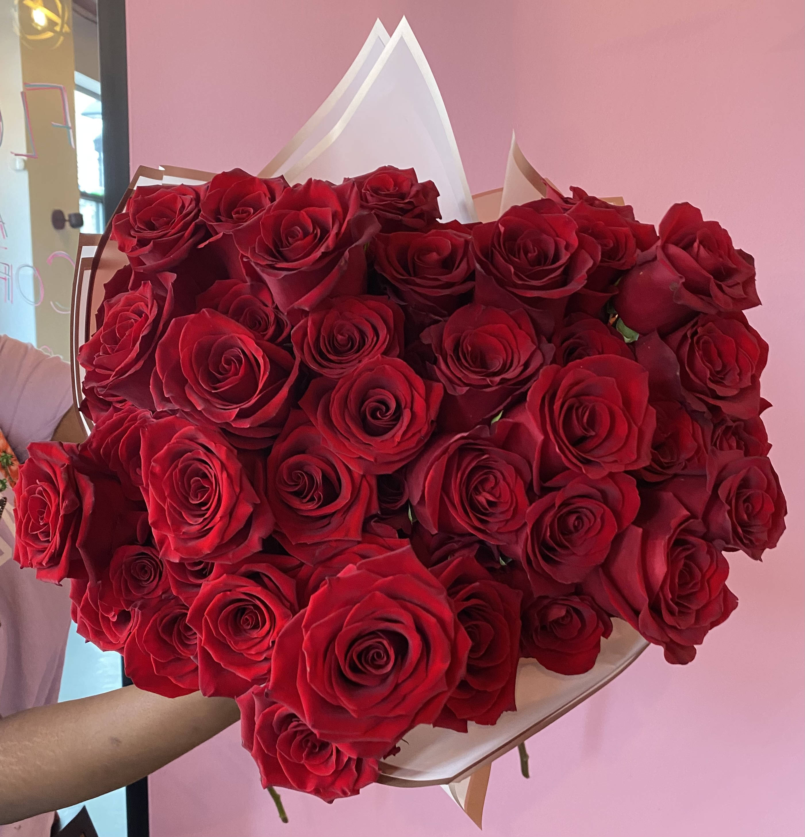 Large bouquet of red roses wrapped in white and tan paper