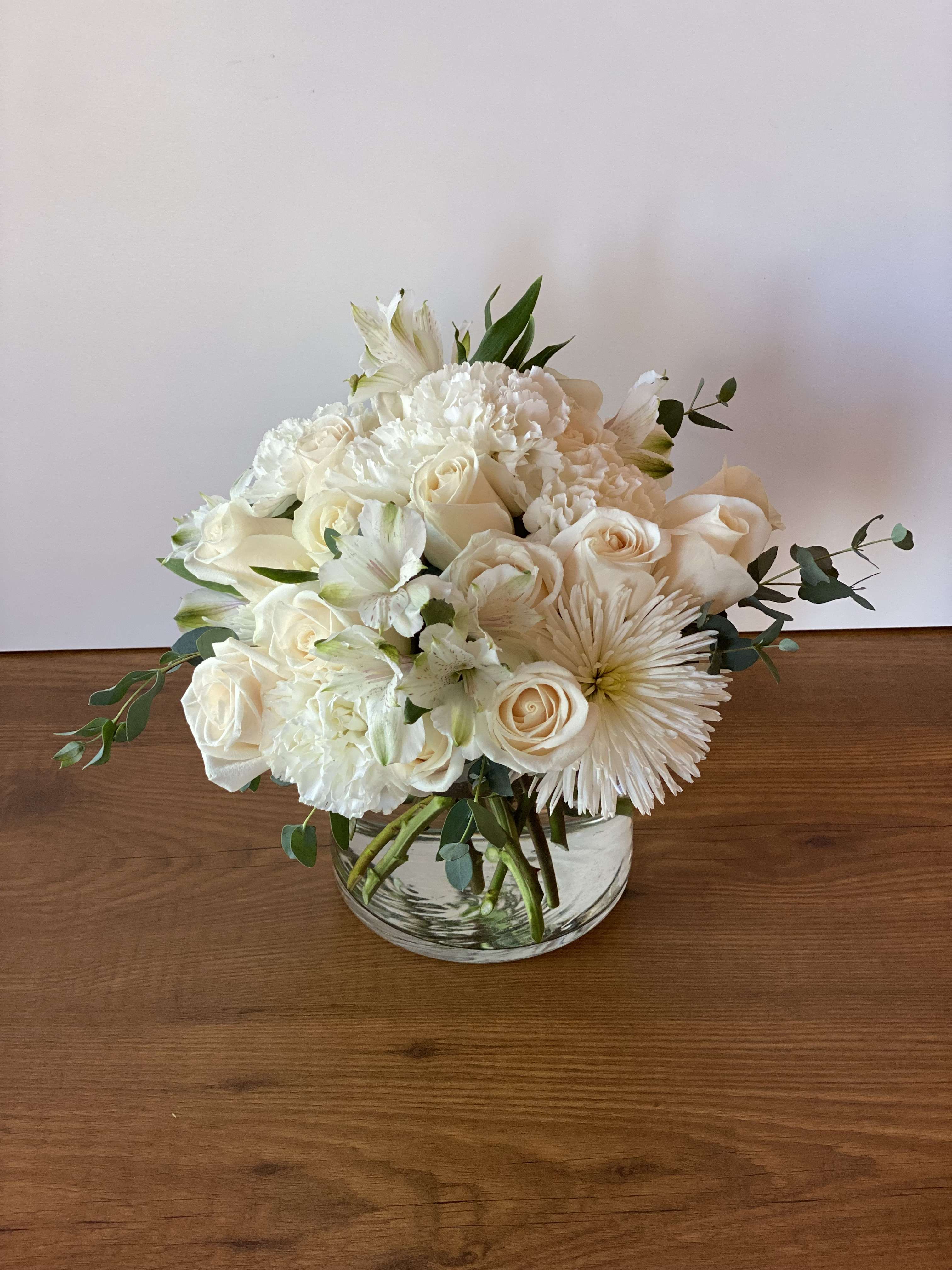 White roses and carnations in a clear glass bowl vase