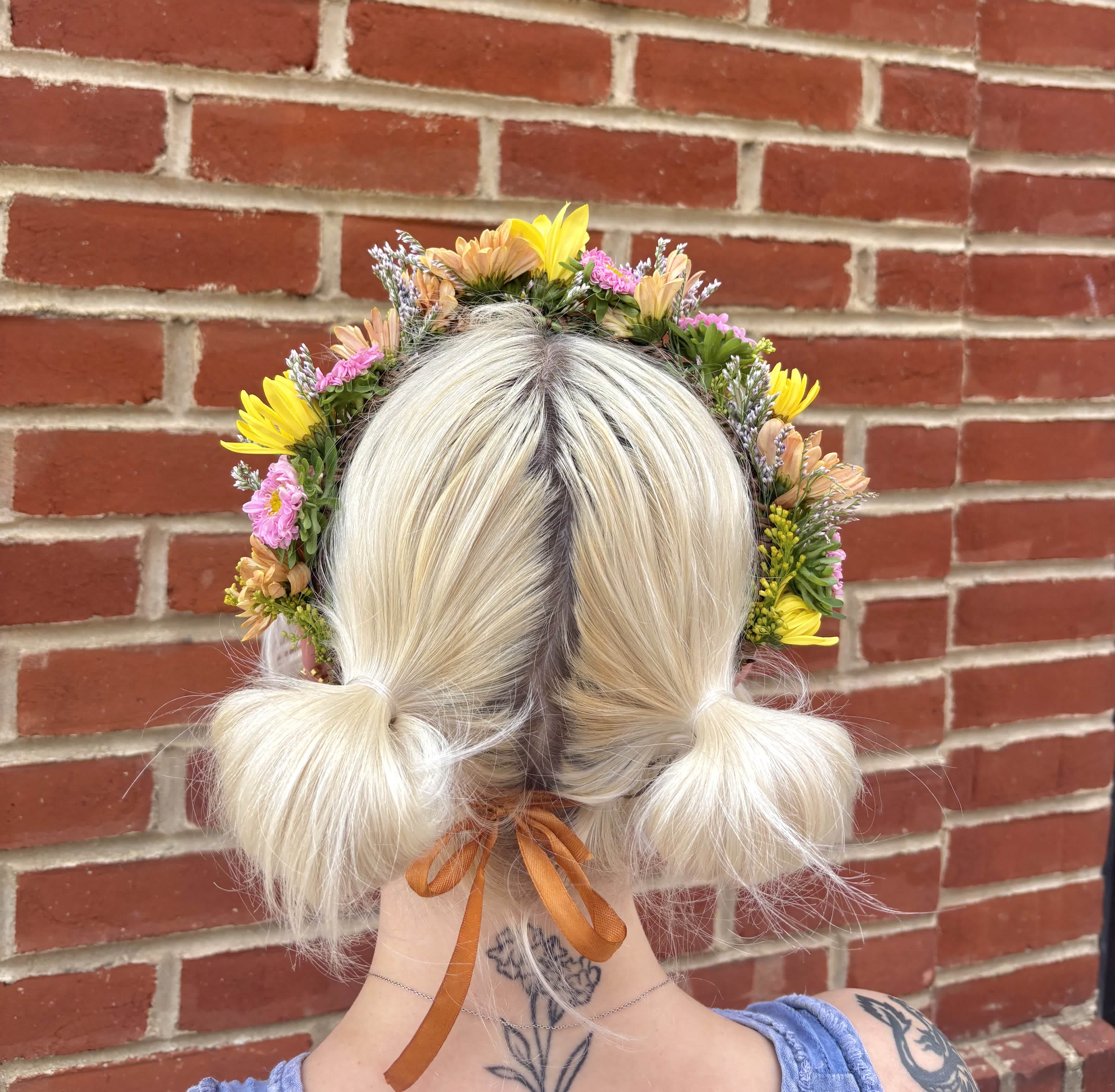 Flower crown on a blonde person with pink and yellow blooms