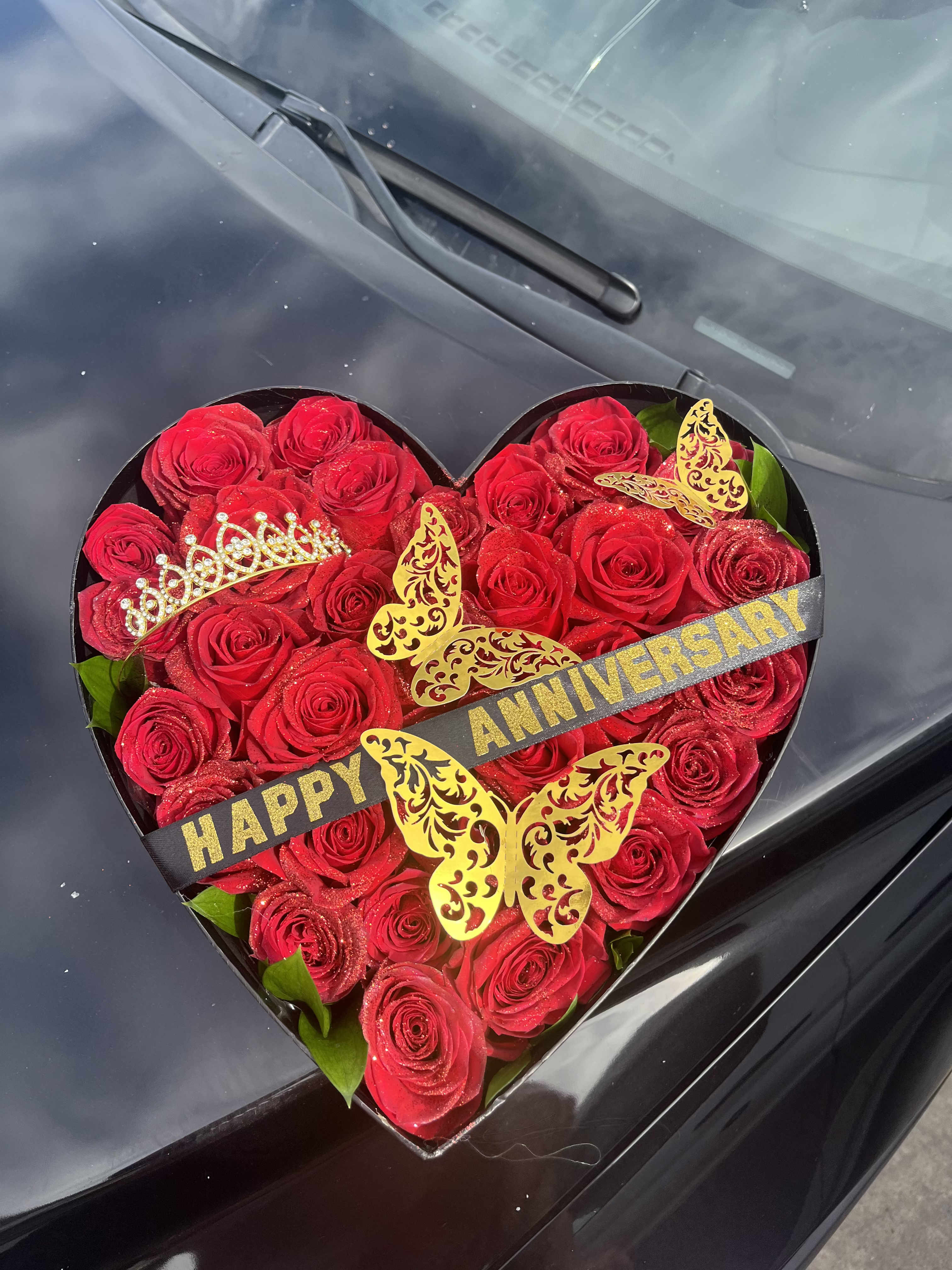 Heart-shaped box of red roses with anniversary ribbon and butterfly decorations