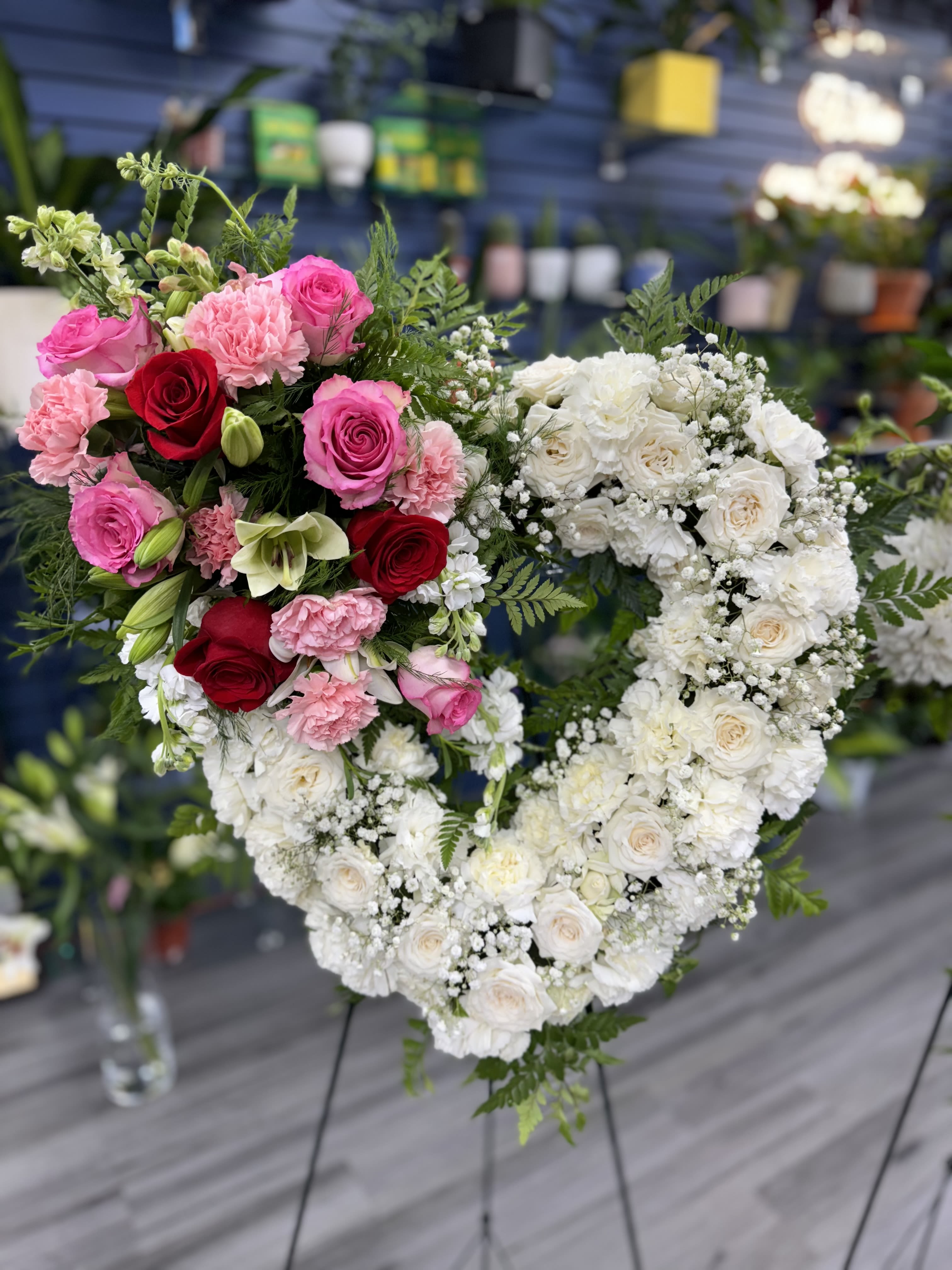 Heart-shaped floral arrangement with pink, red, and white roses