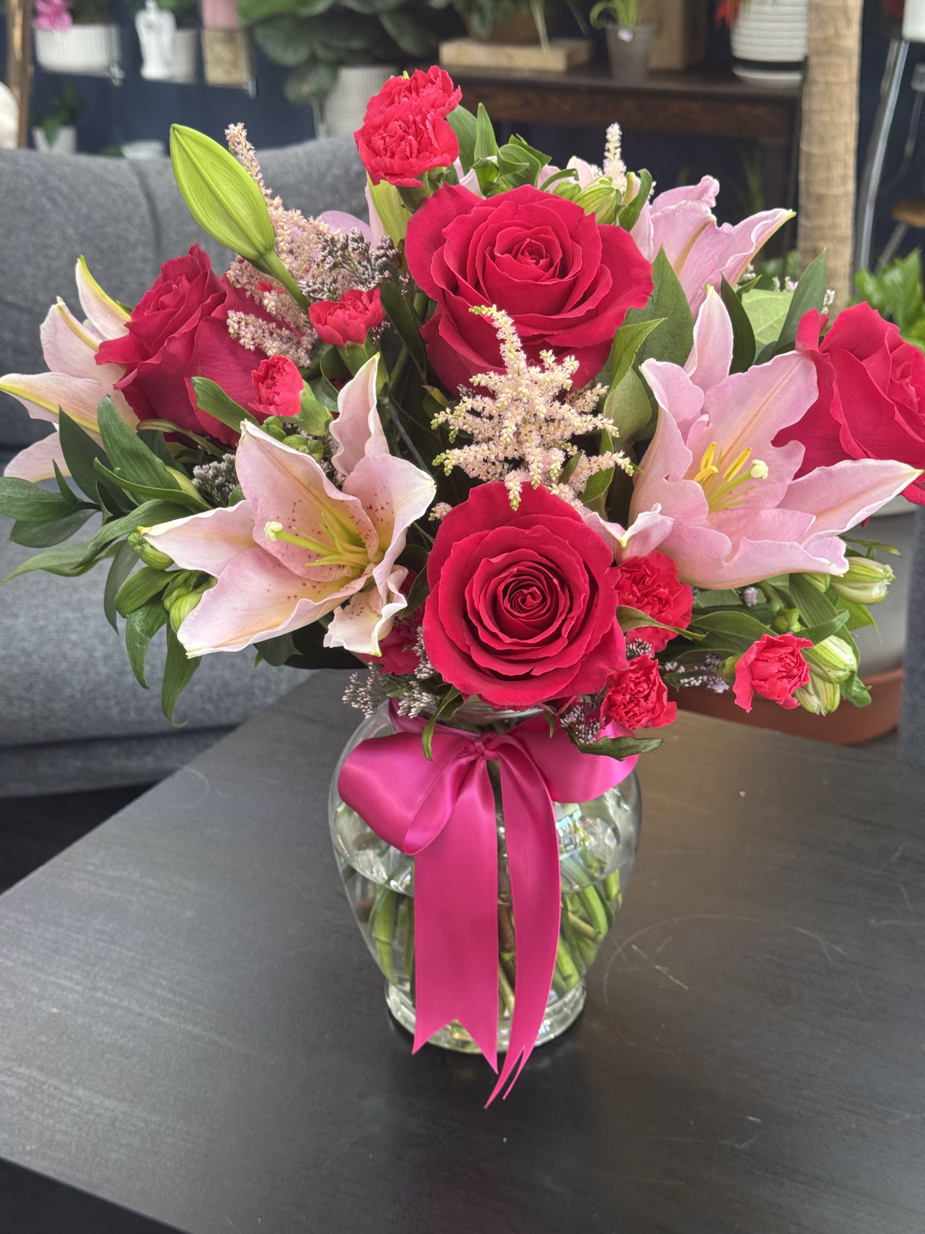 Pink roses and lilies in a glass vase with a ribbon