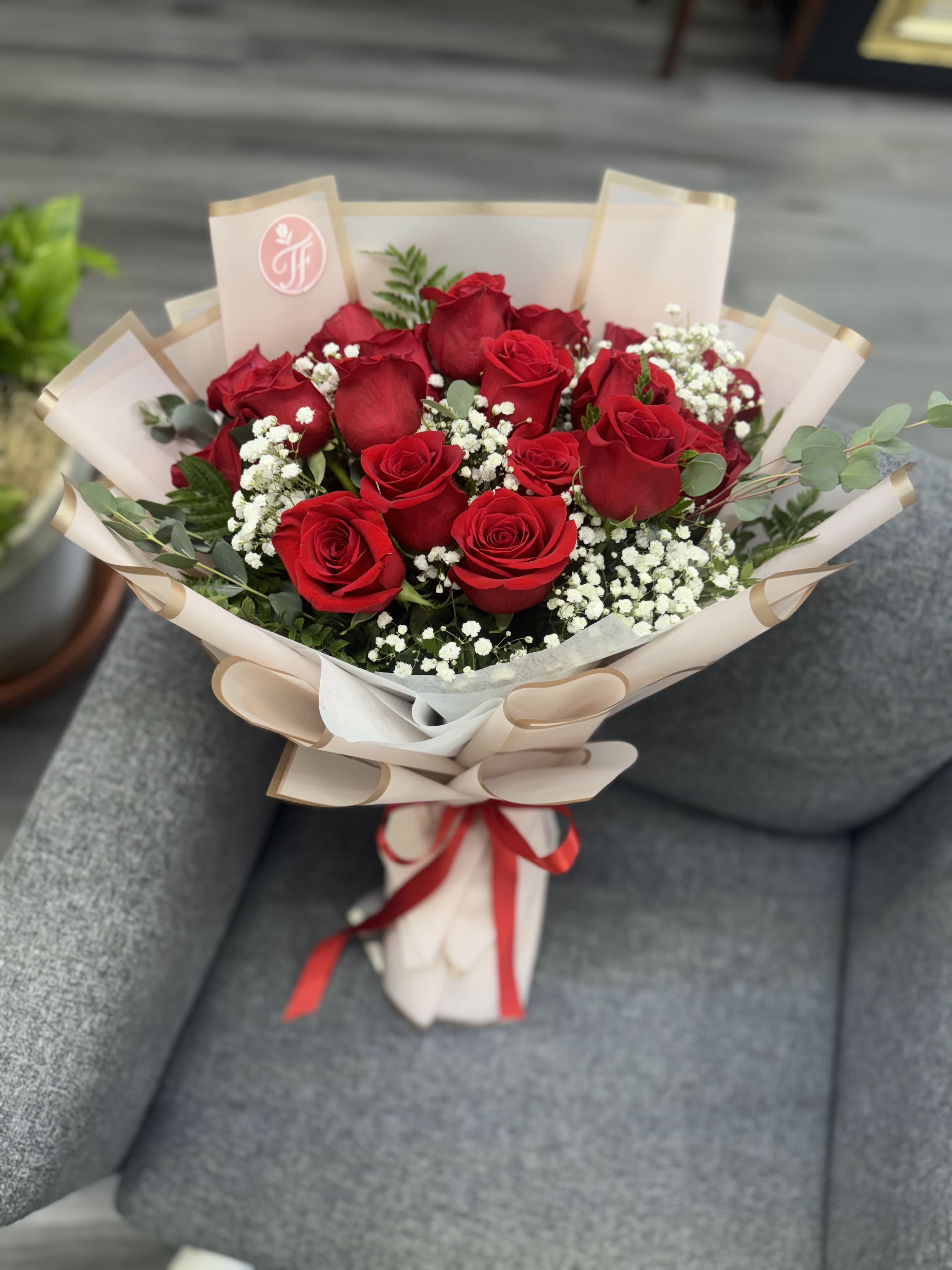Bouquet of red roses with baby's breath in beige wrap