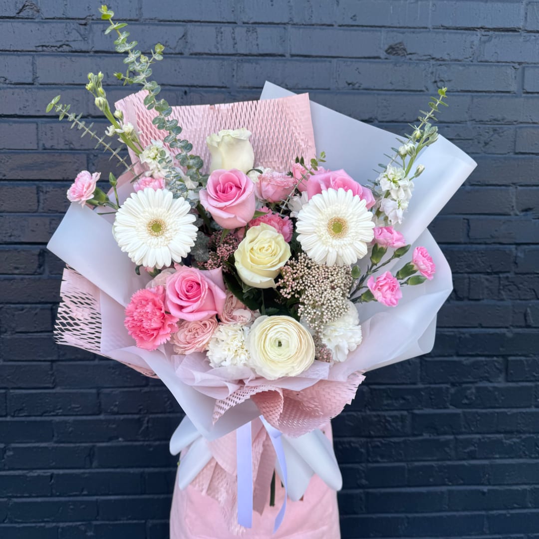 Pink and white mixed bouquet with roses, gerberas, and carnations wrapped in pastel paper