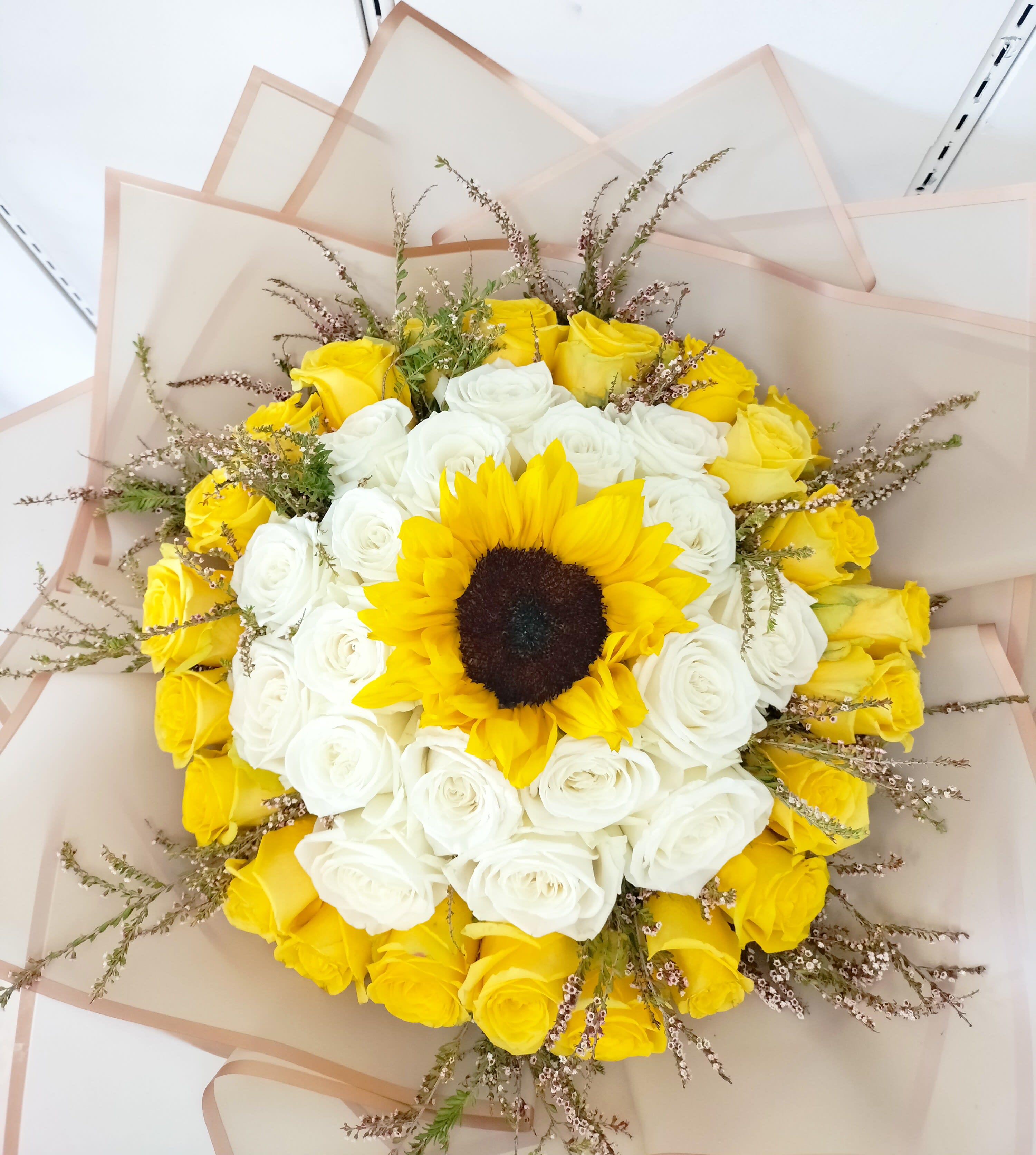 Bouquet of yellow and white roses with a sunflower center