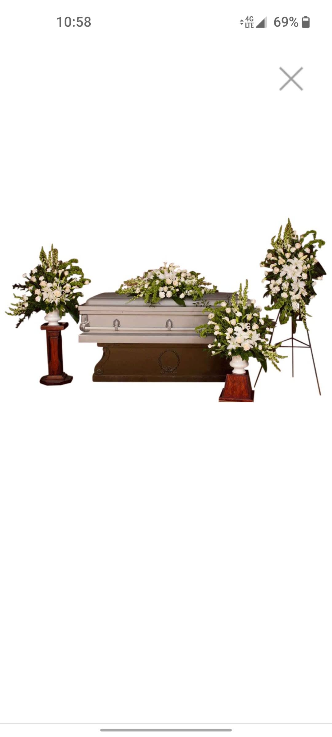 White funeral casket with floral sprays and standing arrangements