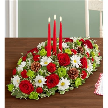 Oval table centerpiece with red roses, white daisies, and three red candles