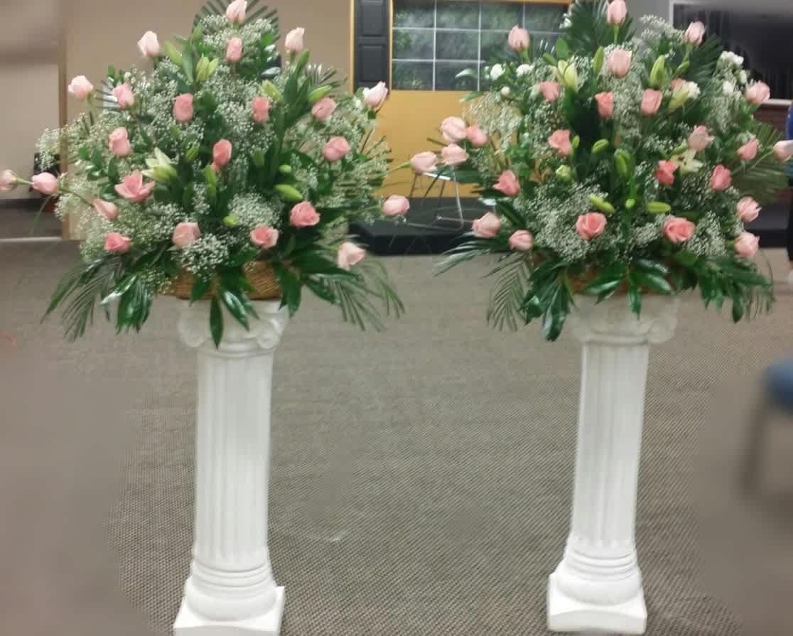 Two pink rose arrangements on white pedestal stands