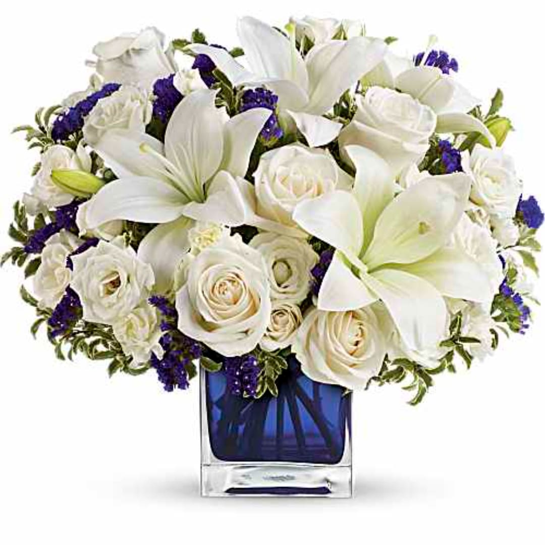 White lilies and roses arranged in a blue glass vase