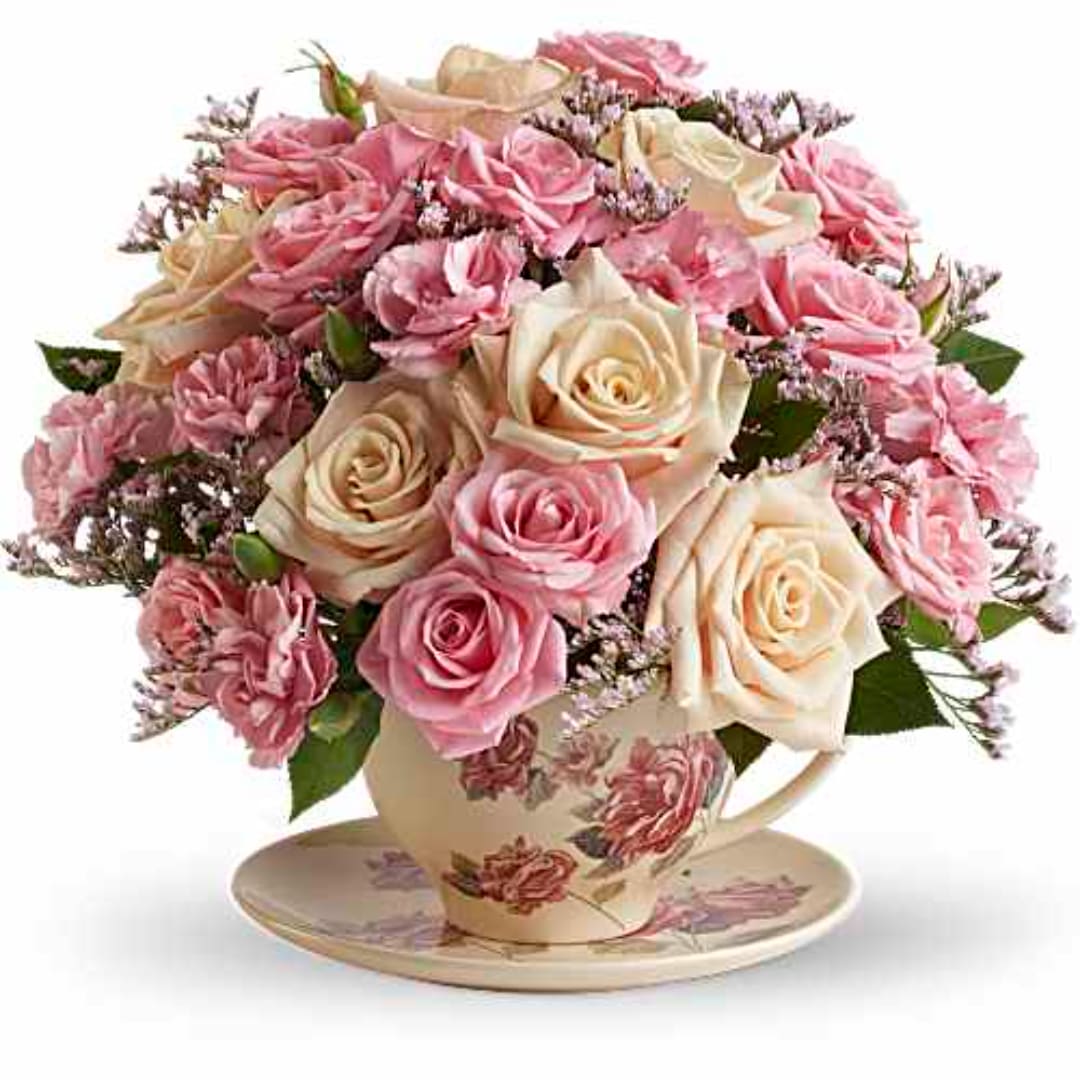 Pink and cream roses arranged in a floral teacup on a saucer