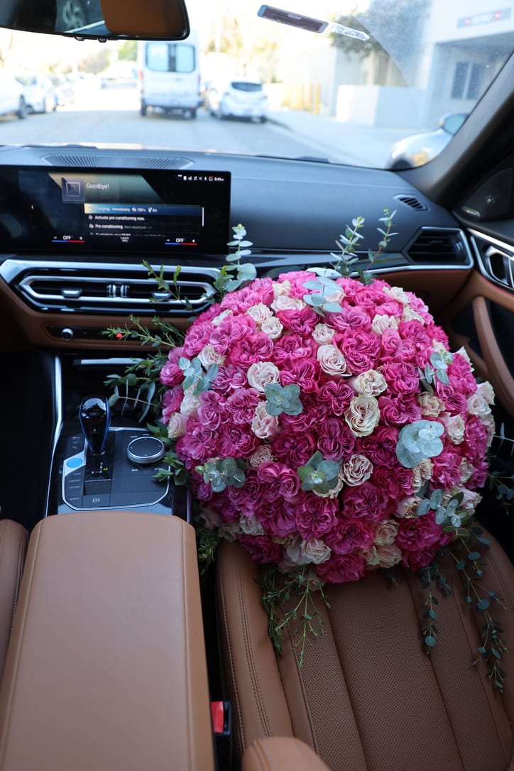Large pink and cream rose bouquet resting on a car seat