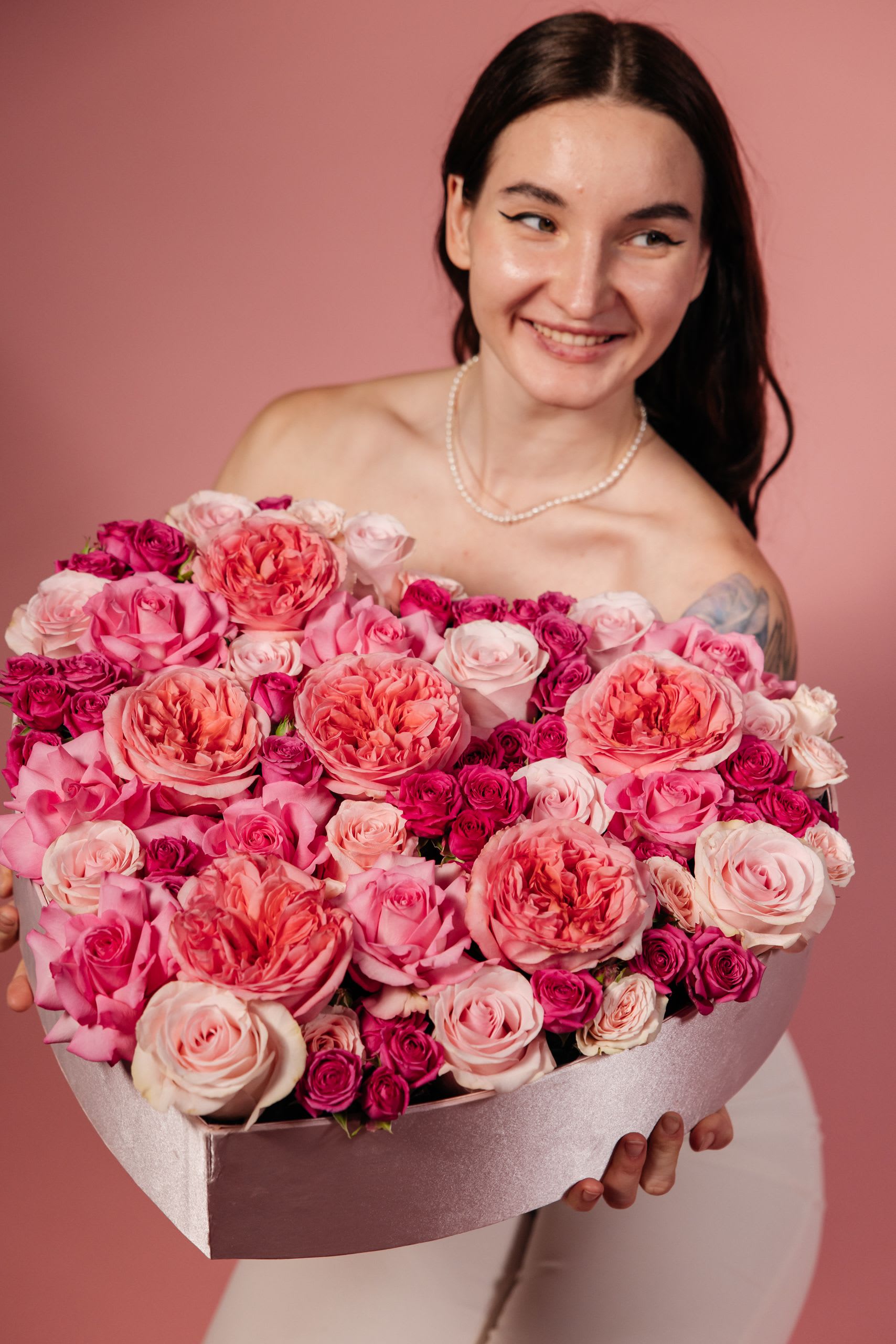 Woman holding a large pink rose bouquet in a box