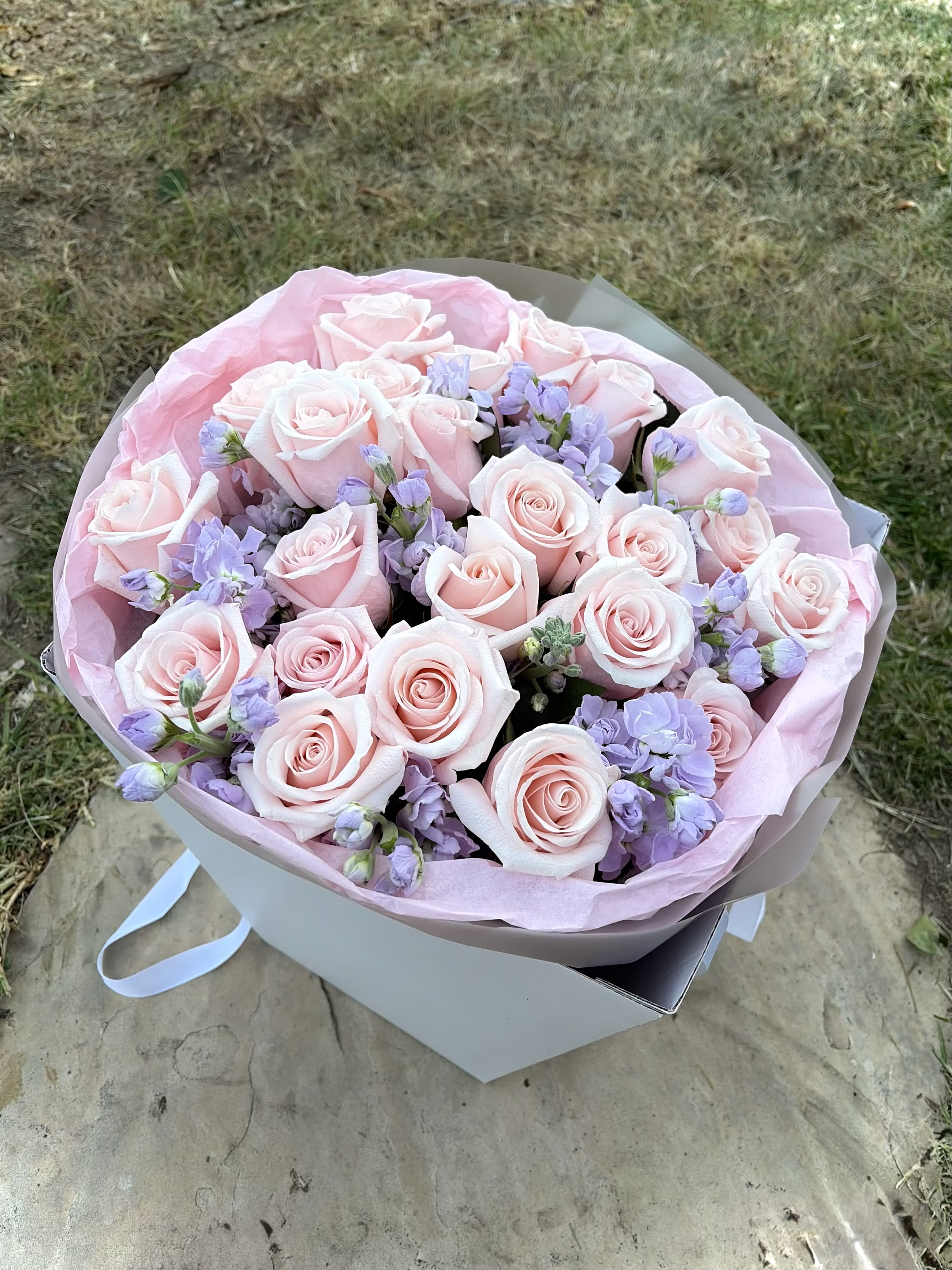 Blush Whisper - Soft, elegant, and effortlessly romantic, Blush Whisper combines premium blush pink roses with delicate lavender stock blooms to create a bouquet that feels like a love letter in floral form. The gentle pastel palette evokes grace, tenderness, and quiet luxury, making it perfect for birthdays, anniversaries, baby showers, thank-you gifts, or simply brightening someone’s day.  Designed with timeless beauty in mind, this arrangement offers a refined and feminine aesthetic that never goes out of style.  Includes:  * Premium blush pink roses * Lavender stock flowers * Fresh seasonal greenery * Luxury wrapping and ribbon